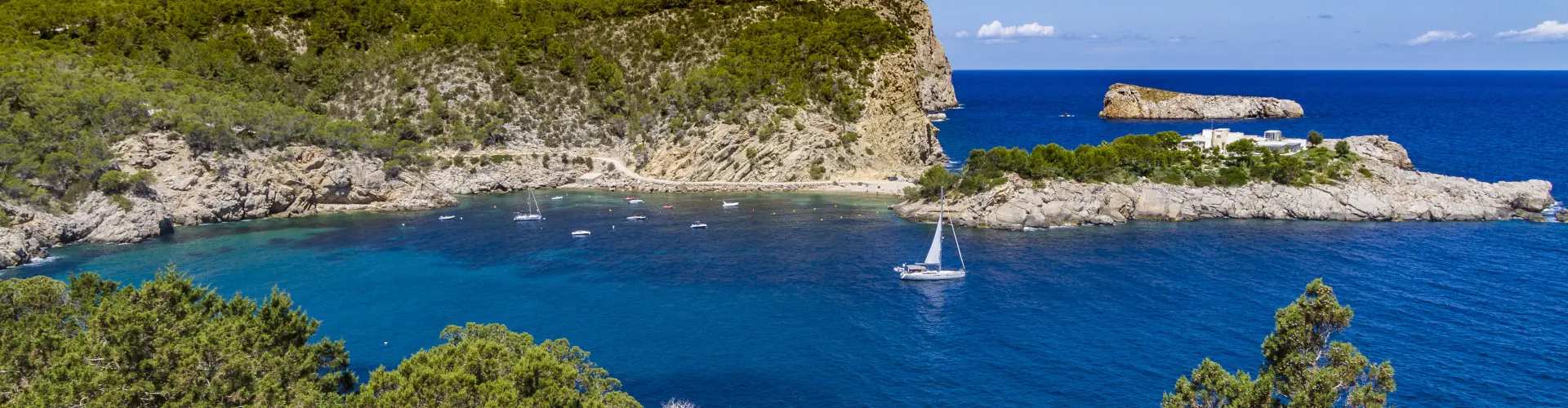 Tranquila Cala Sa Ferradura, una hermosa bahía rodeada de acantilados y aguas cristalinas en la costa de Ibiza.