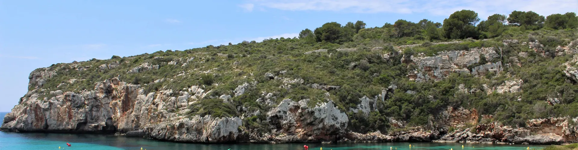 Calma y belleza en Es Canutells, una pintoresca cala de aguas turquesas rodeada de acantilados y naturaleza en Menorca