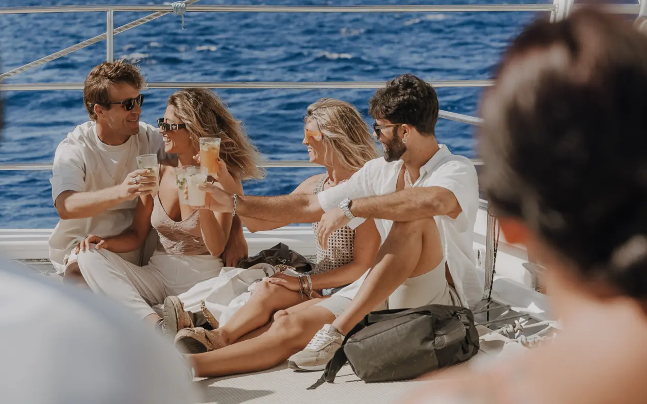 Un grupo de pasajeros disfruta del trayecto mientras el barco se desliza por el agua, con risas, sol y brisa marina.