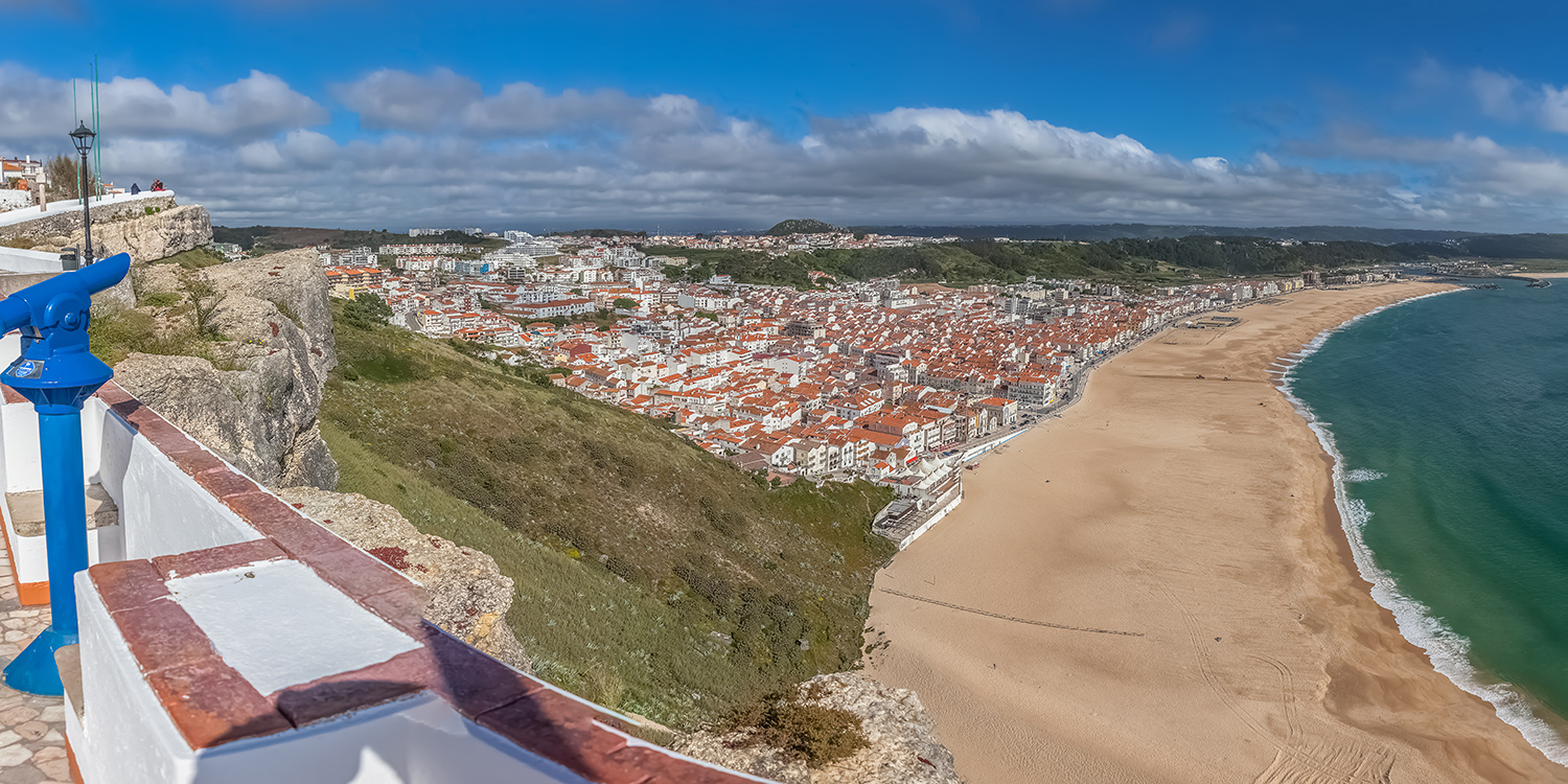 Panorámica de Nazaré con su amplia playa y casas junto al acantilado.
