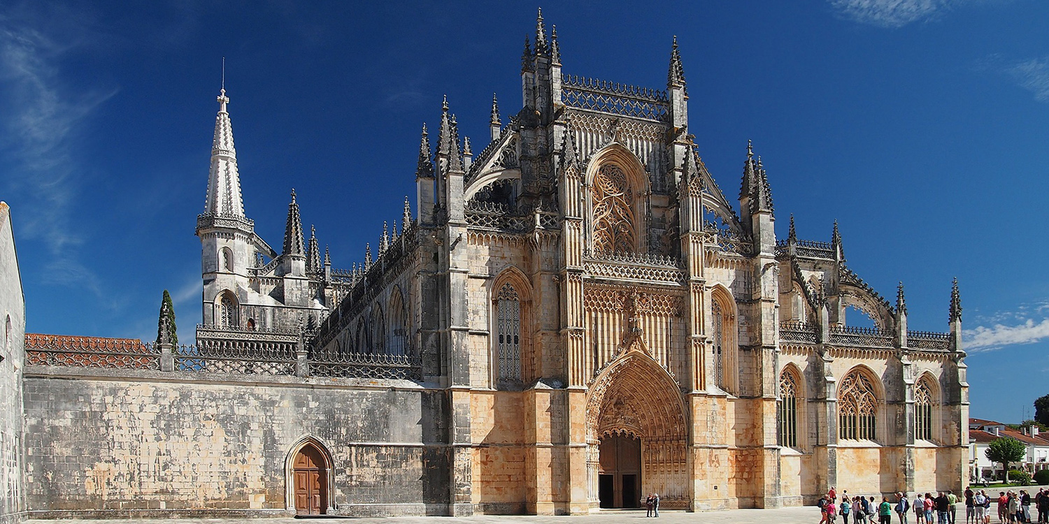 Fachada gótica del Monasterio de Batalha bajo un cielo azul despejado.