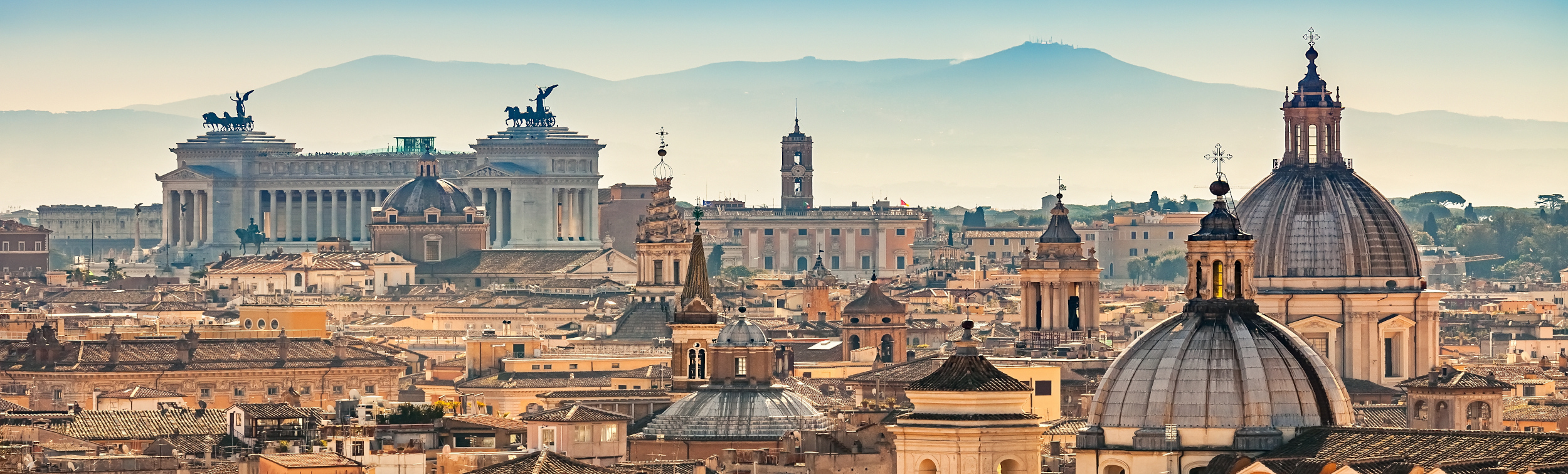 Panorámica de Roma con cúpulas históricas y el Altar de la Patria al fondo.