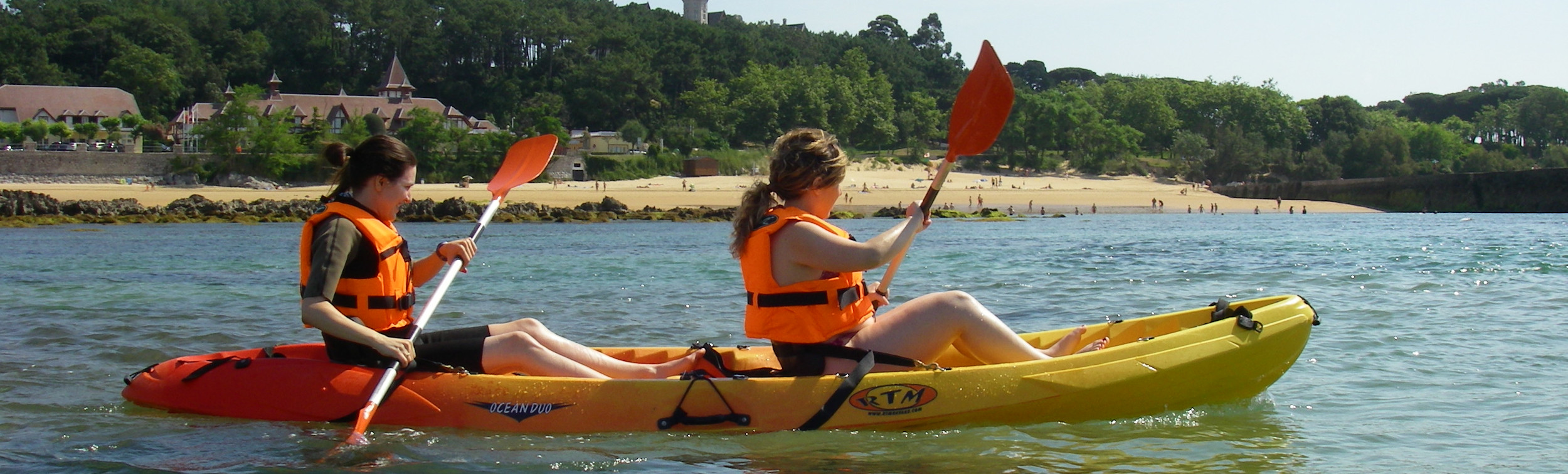 Personas remando en kayak doble con chalecos salvavidas en la bahía de Santander, Cantabria