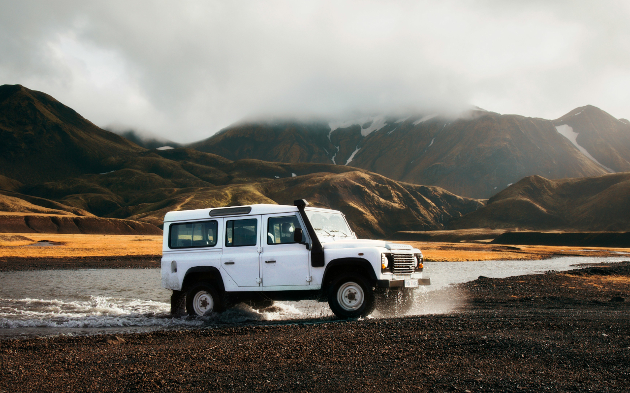 Vehículo 4x4 cruzando un arroyo entre montañas en un paisaje natural.