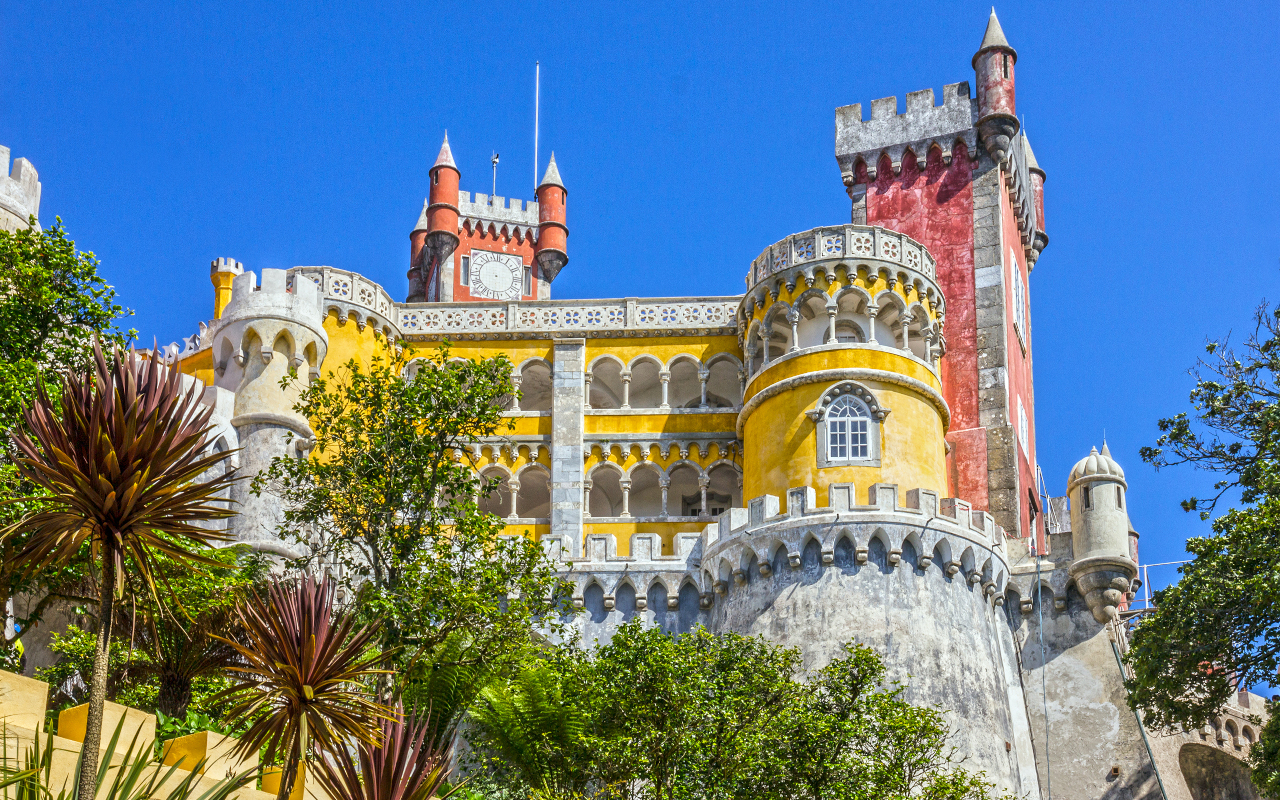 Fachada colorida del Palacio da Pena en Sintra entre árboles.