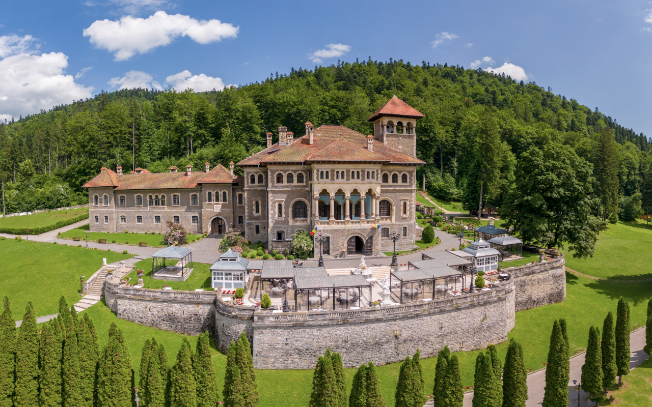 Panorámica del Castillo de Cantacuzino y su entorno, con vegetación y montañas alrededor del edificio.