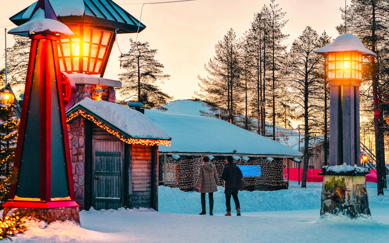 Pareja paseando por el pueblo de Papá Noel al atardecer.