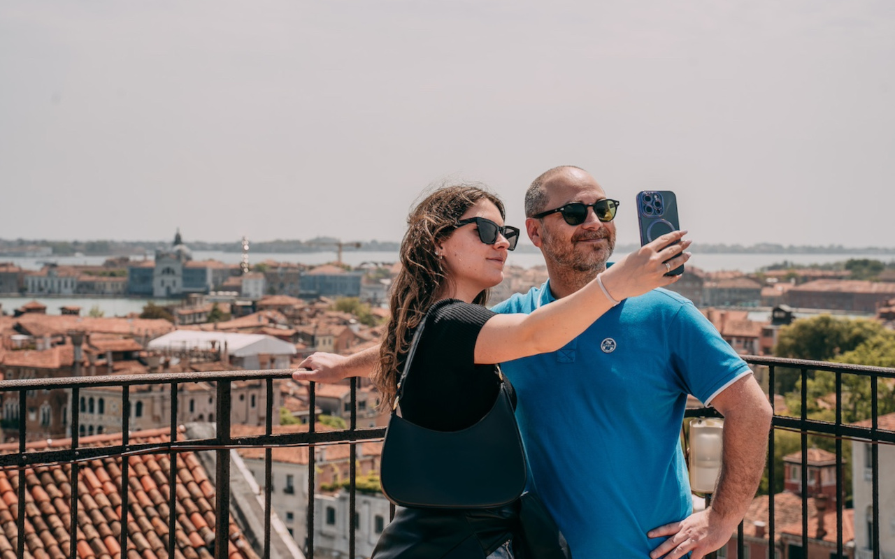 Pareja se hace una fotografía con las panorámicas de Venecia de fondo.