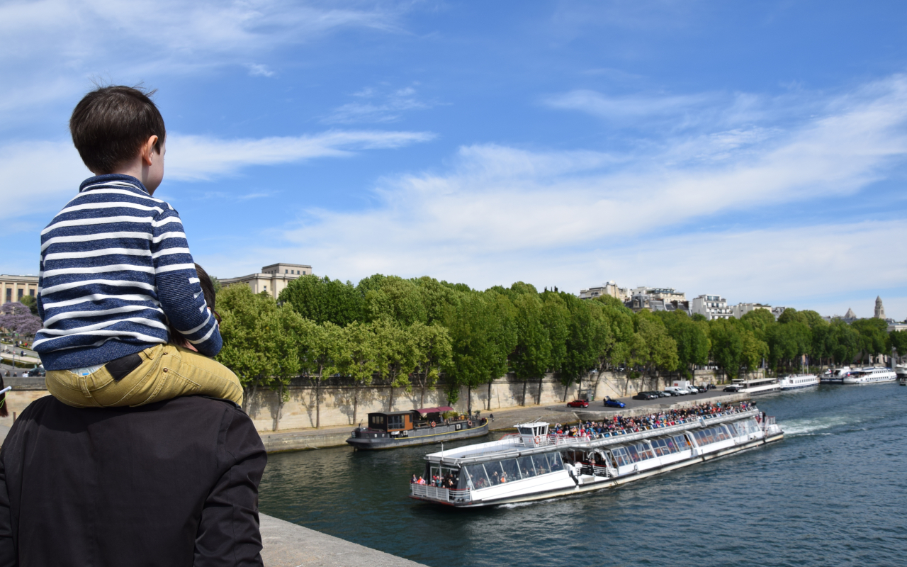 Familia observando un bateau mouche, uno de los barcos más famosos de París que navegan el río Sena.