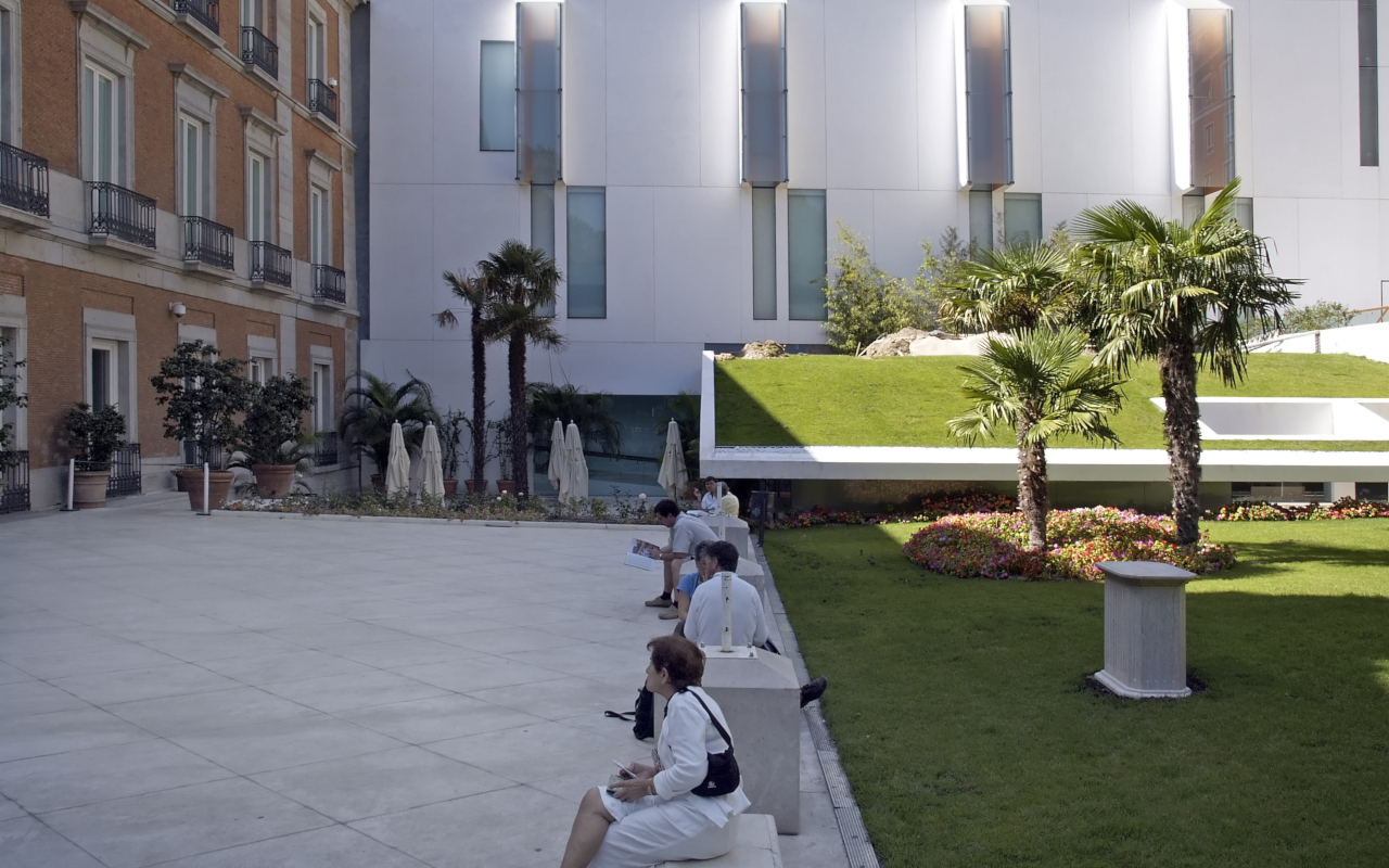 Edificio del Museo Thyssen con gente descansando en bancos.