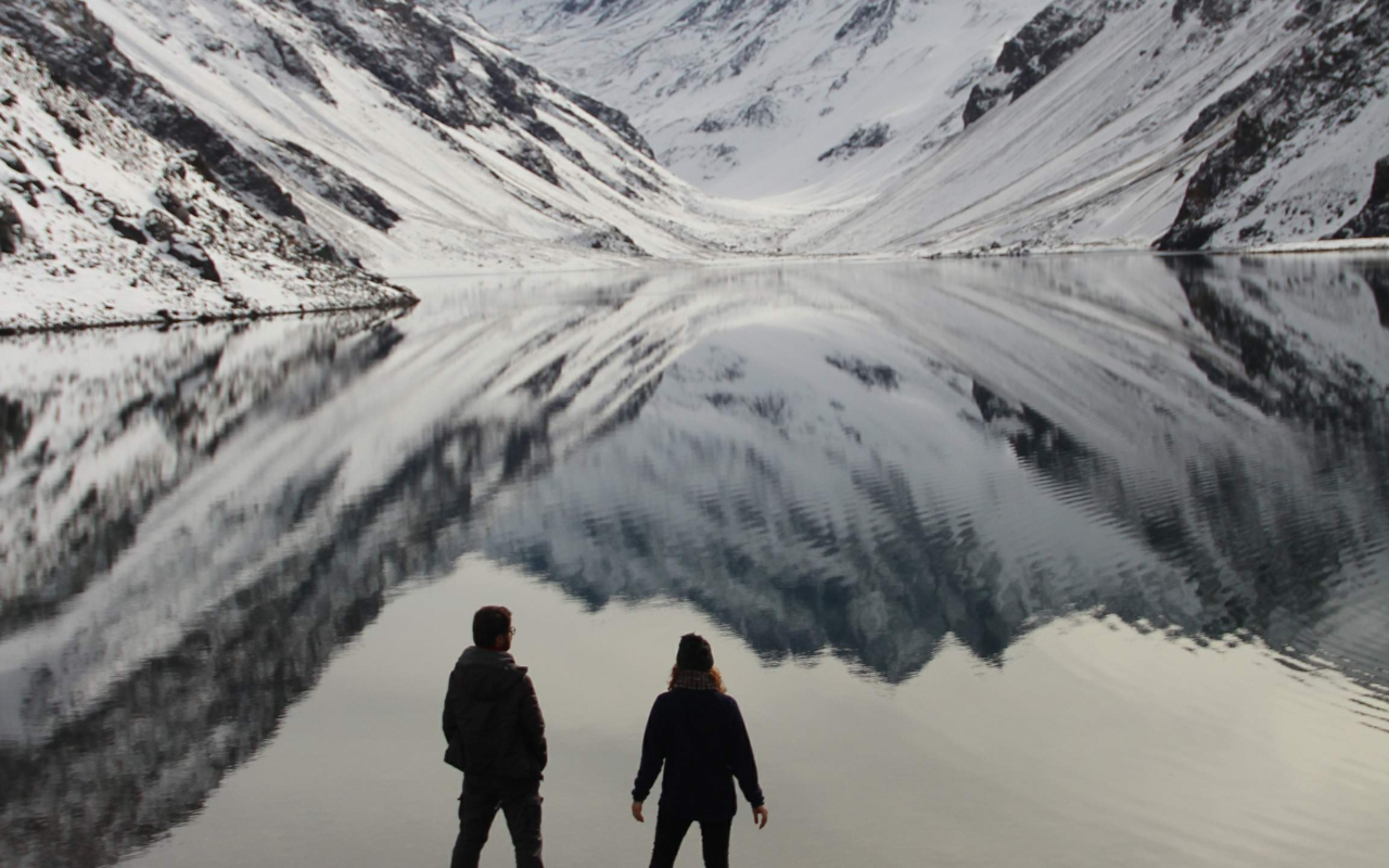 Pareja con las montañas de los Andes reflejadas en la Laguna del Inca en la excursión desde Santiago de Chile.
