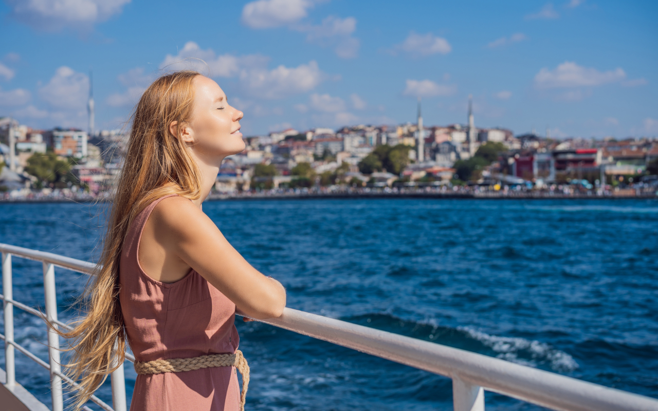 Chica disfruta del sol desde un barco por el Bósforo