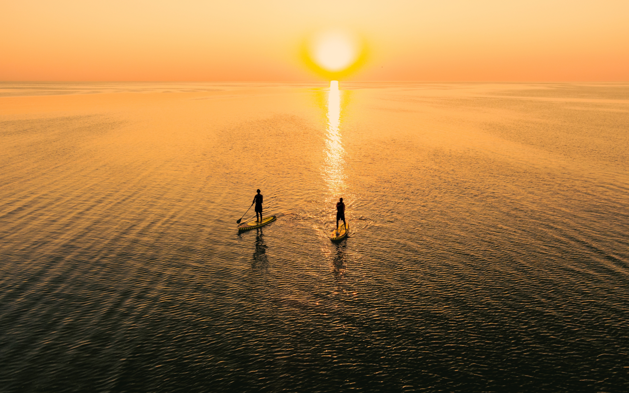 Atardecer en Mallorca con personas haciendo paddle surf