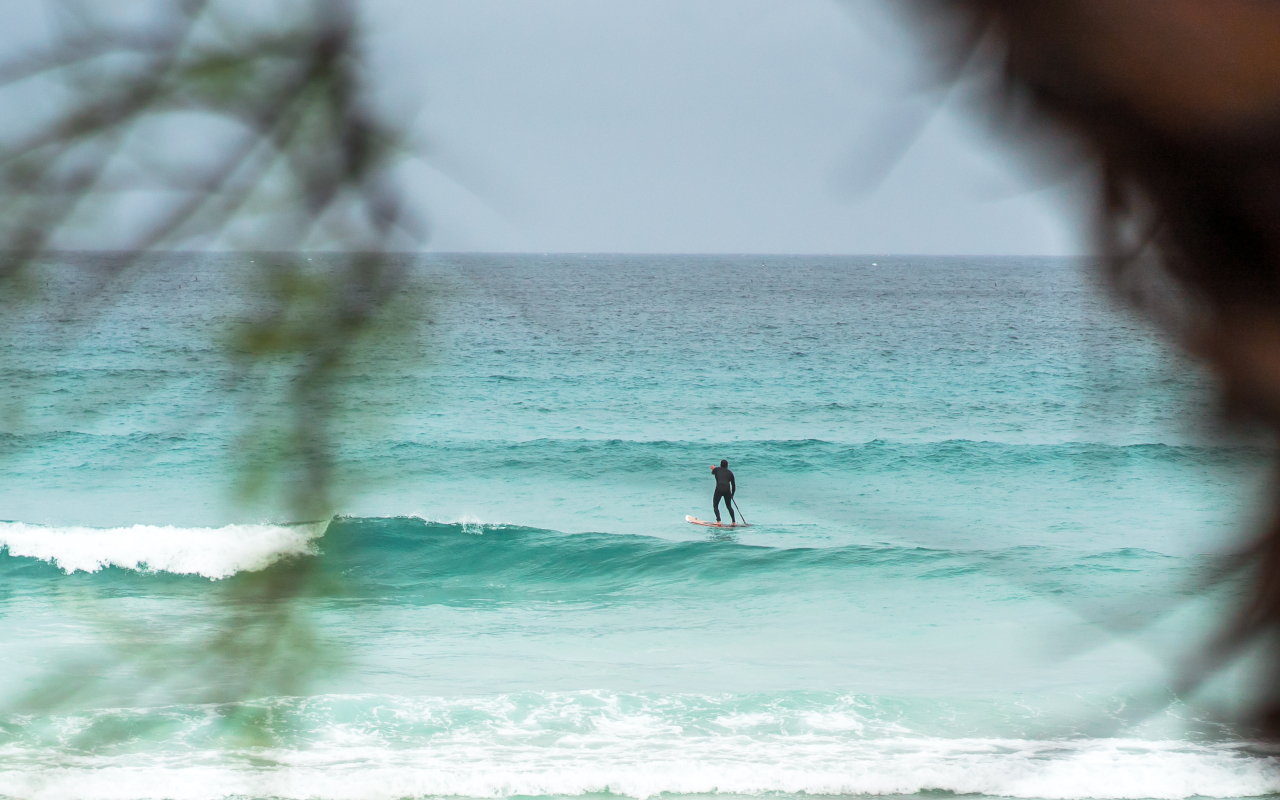 Una persona practica paddle surf a través de las olas en Cala Ratjada, Mallorca