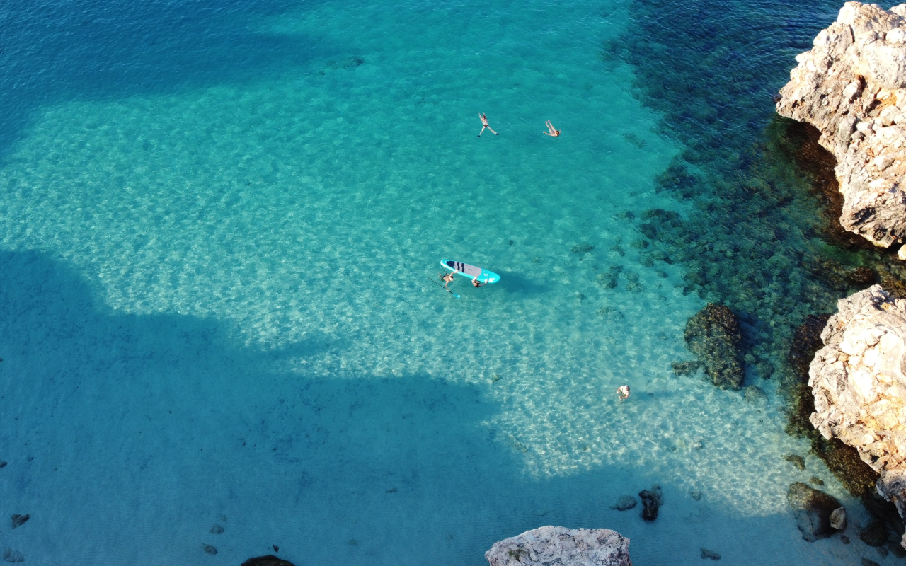 Vista aérea de un grupo de personas practicando paddle surf y snorkel en Cala Ratjada, Mallorca