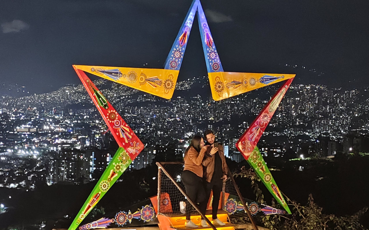 Pareja se realiza una fotografía en uno de los miradores de Medellín con un marco de colores.