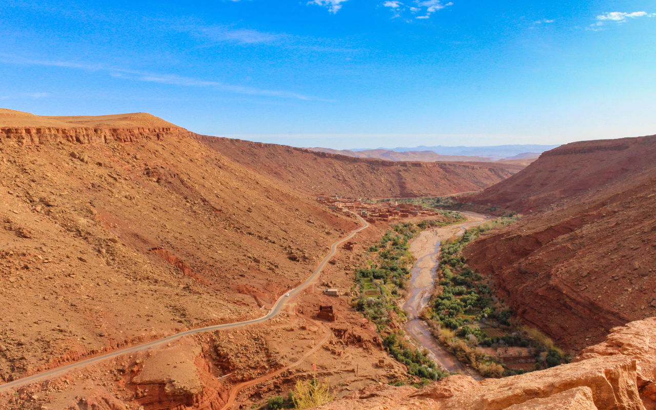 Vista panorámica de las carreteras serpenteantes del Alto Atlas entre colinas áridas y un río rodeado de vegetación