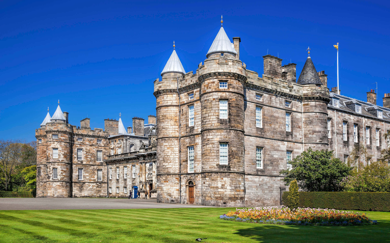 Fachada principal del Palacio de Holyroodhouse en Edimburgo bajo un cielo azul despejado