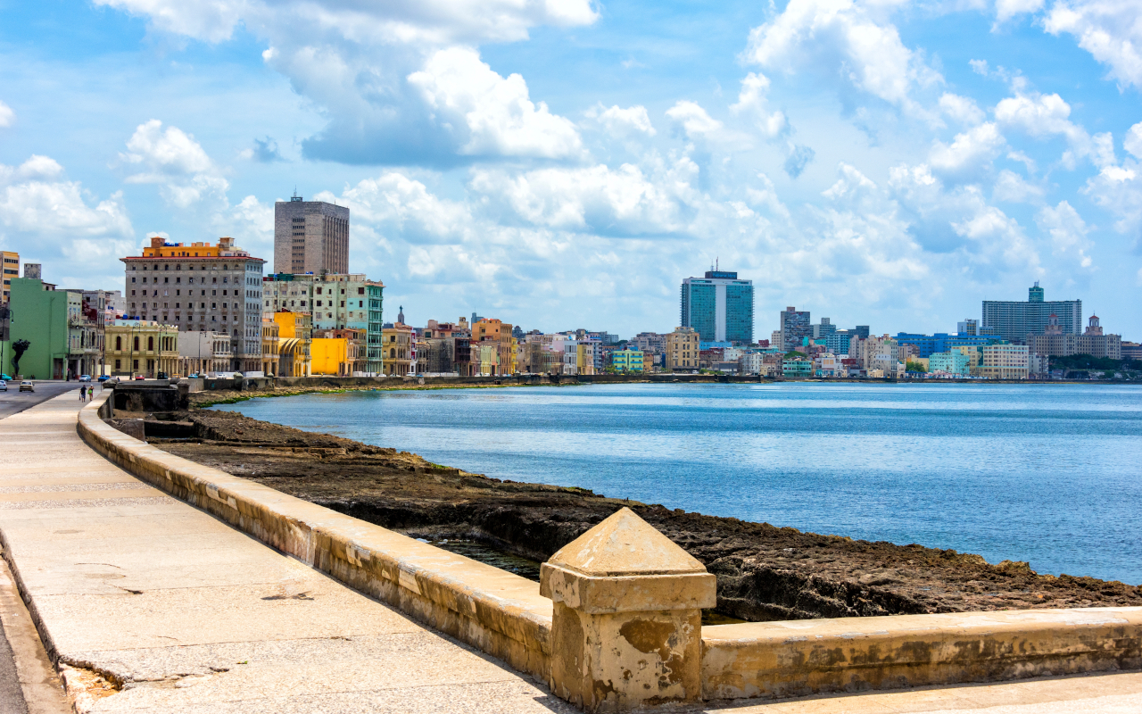Vista del Malecón habanero con el mar al atardecer y el skyline de edificios coloniales al fondo.