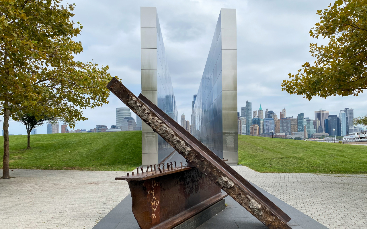 Monumento conmemorativo del 11S con vigas de acero y vista de Manhattan desde Liberty State Park.