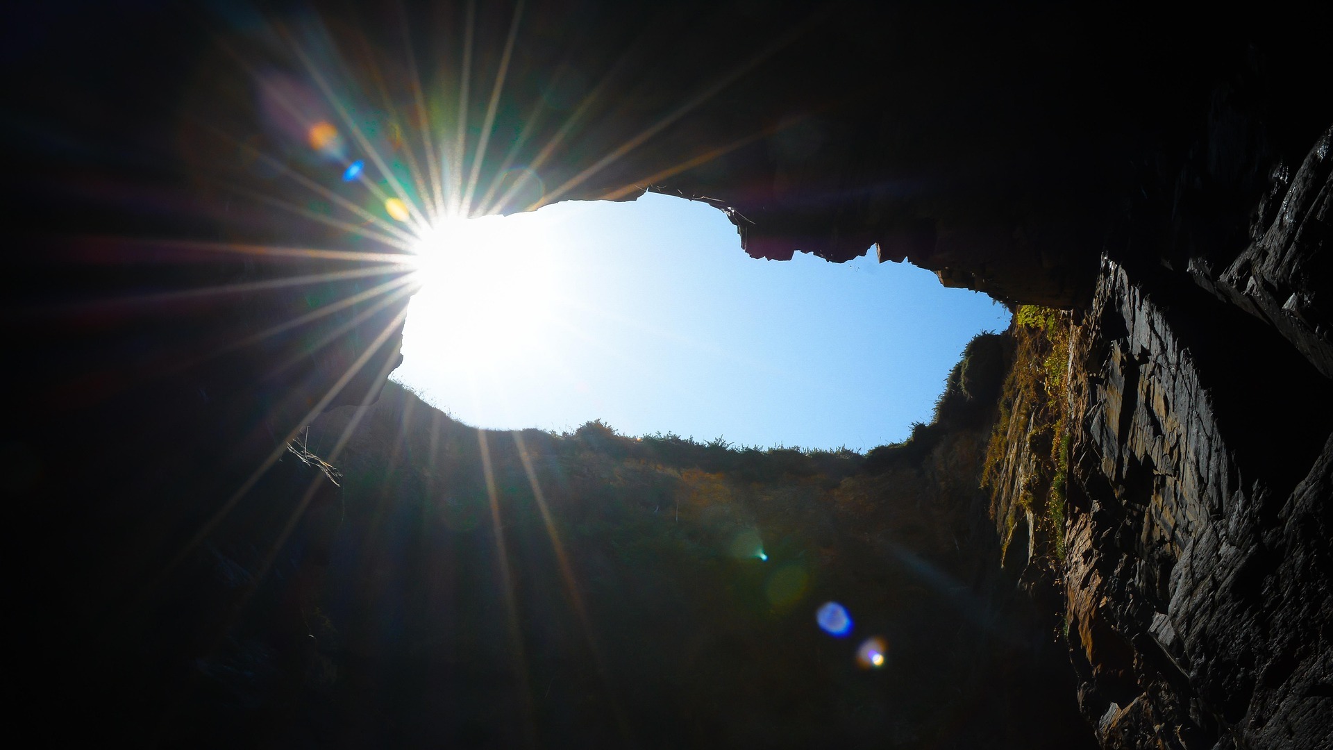 Interior de cueva en la Playa de las Catedrales, Ribadeo, Galicia, con el sol brillando intensamente.