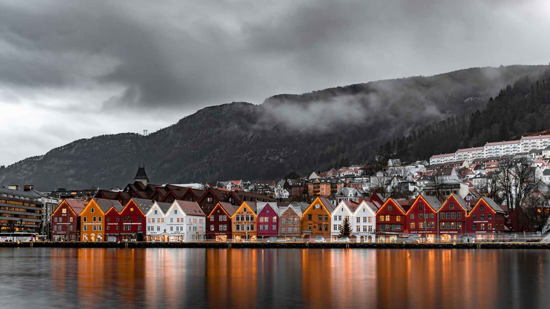 Famoso muelle de Bryggen en Bergen, Noruega, con casas de madera coloridas reflejadas en el agua al anochecer.