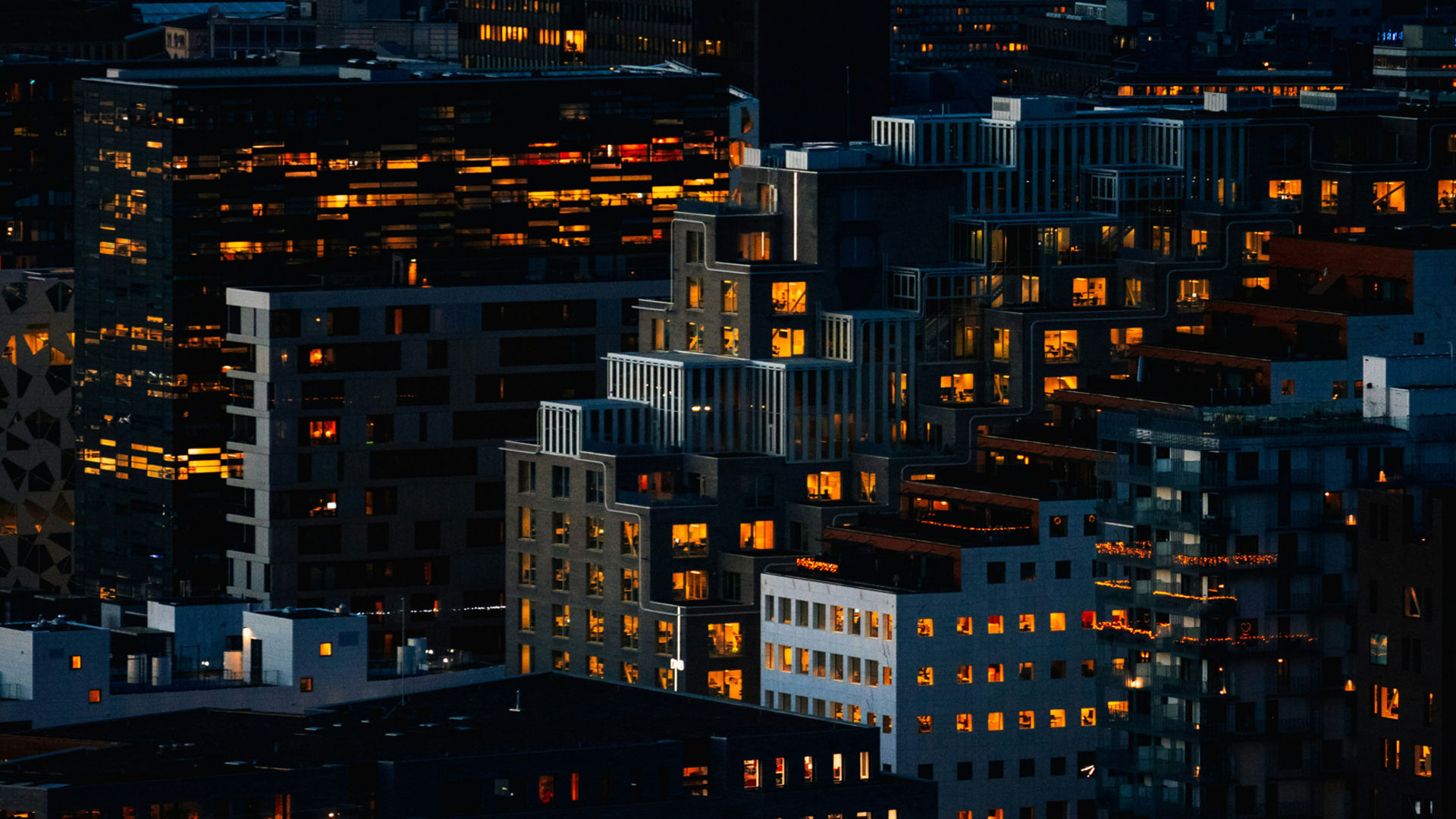 Edificios modernos iluminados al anochecer en el barrio de Bjørvika, Oslo, con arquitectura contemporánea.