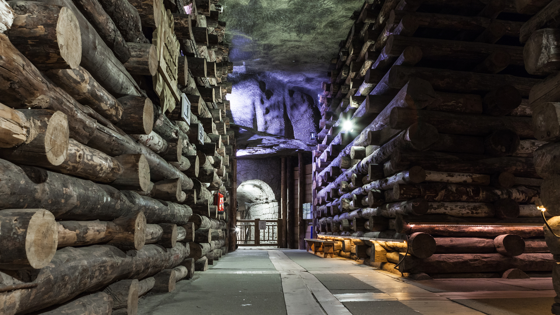 Interior de las minas de sal de Wieliczka en Polonia, con paredes cubiertas de troncos de madera y poca luz.