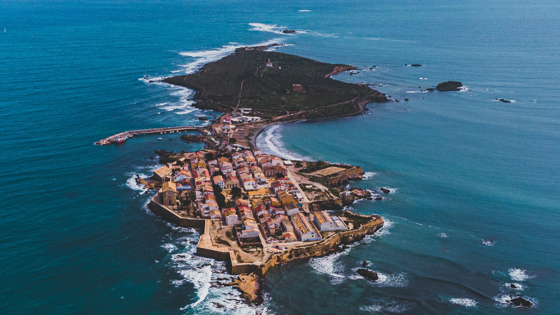 Vista aérea de la isla de Tabarca, mostrando el pueblo amurallado y la parte natural rodeada de mar azul.