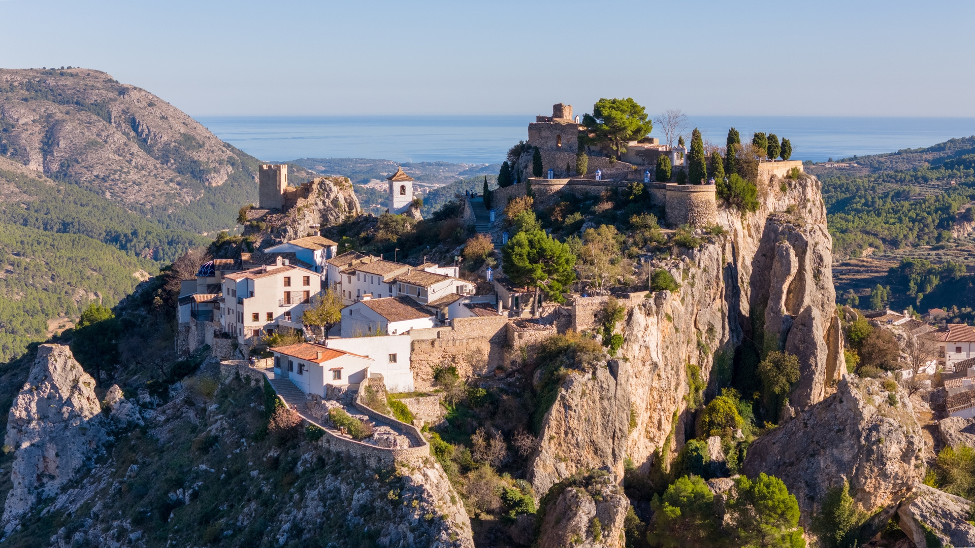 Vista aérea del encantador pueblo de Guadalest, con su castillo y casas medievales, sobre una roca y con vistas al mar.