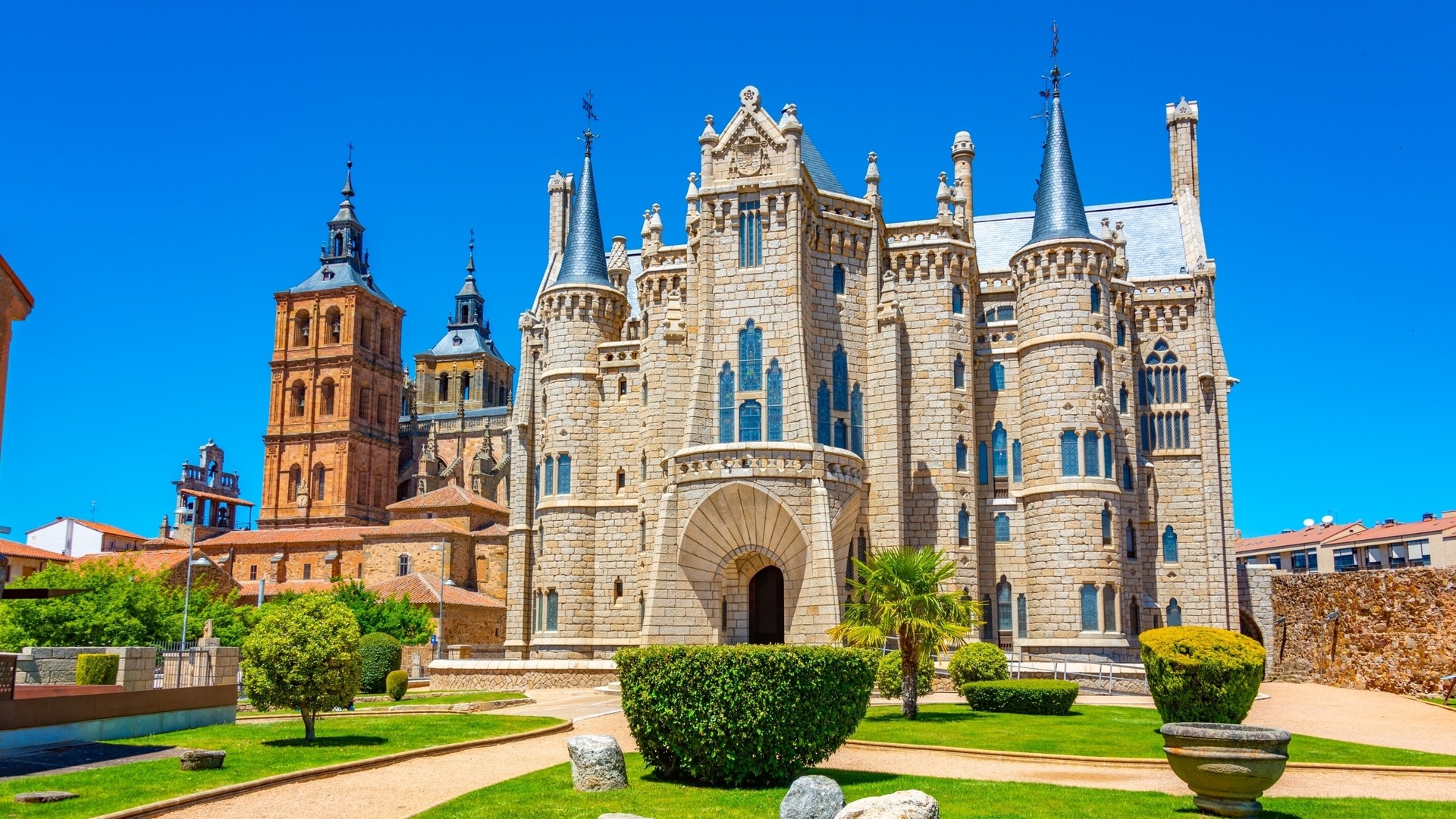 Palacio Episcopal de Astorga, León, diseño neogótico de Gaudí, con torres, jardines y la Catedral al fondo.