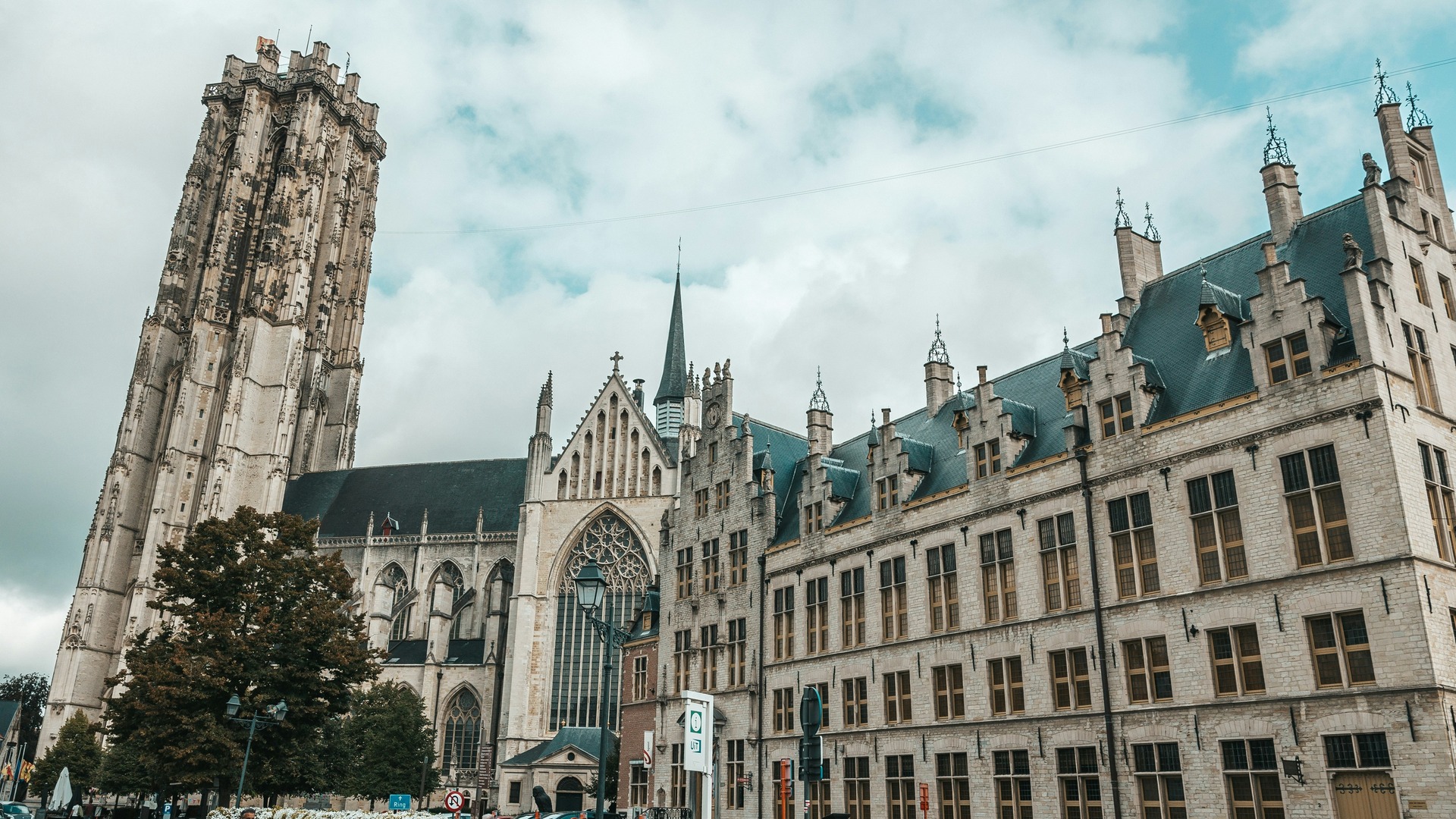 Torre de San Rumoldo y edificios históricos de la Grote Markt en Malinas (Mechelen), Bélgica, bajo cielo nublado.