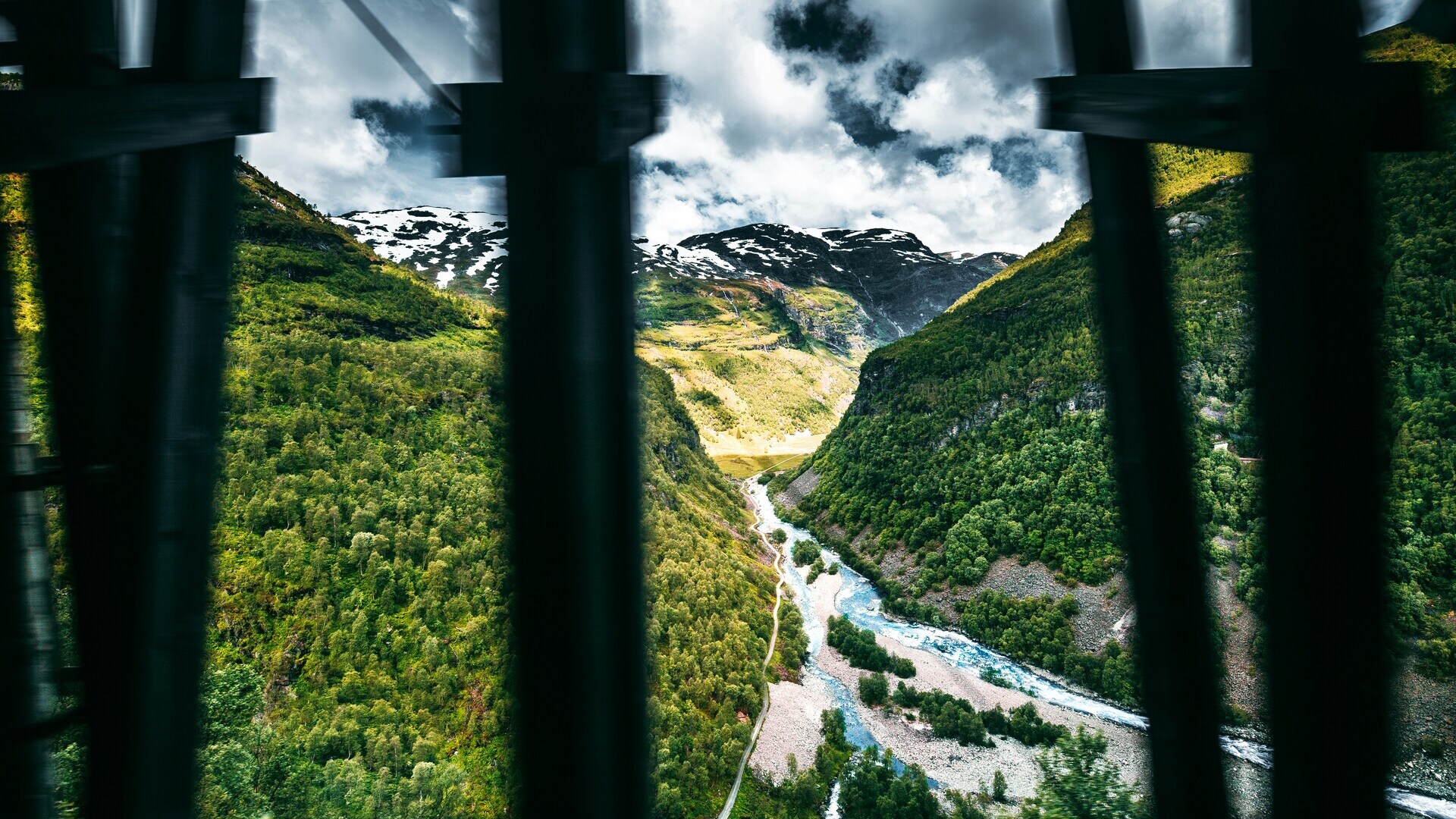 Vista impresionante del valle y río Kjosfossen desde Myrdal, Noruega, con frondosos bosques y montañas nevadas.