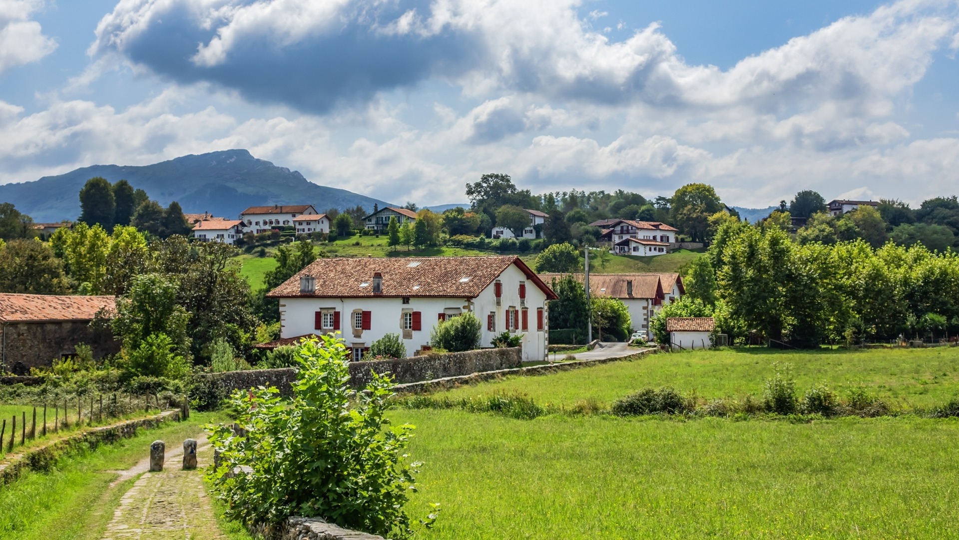 Casas blancas con contraventanas rojas entre prados verdes en Sare, en el País Vasco francés.