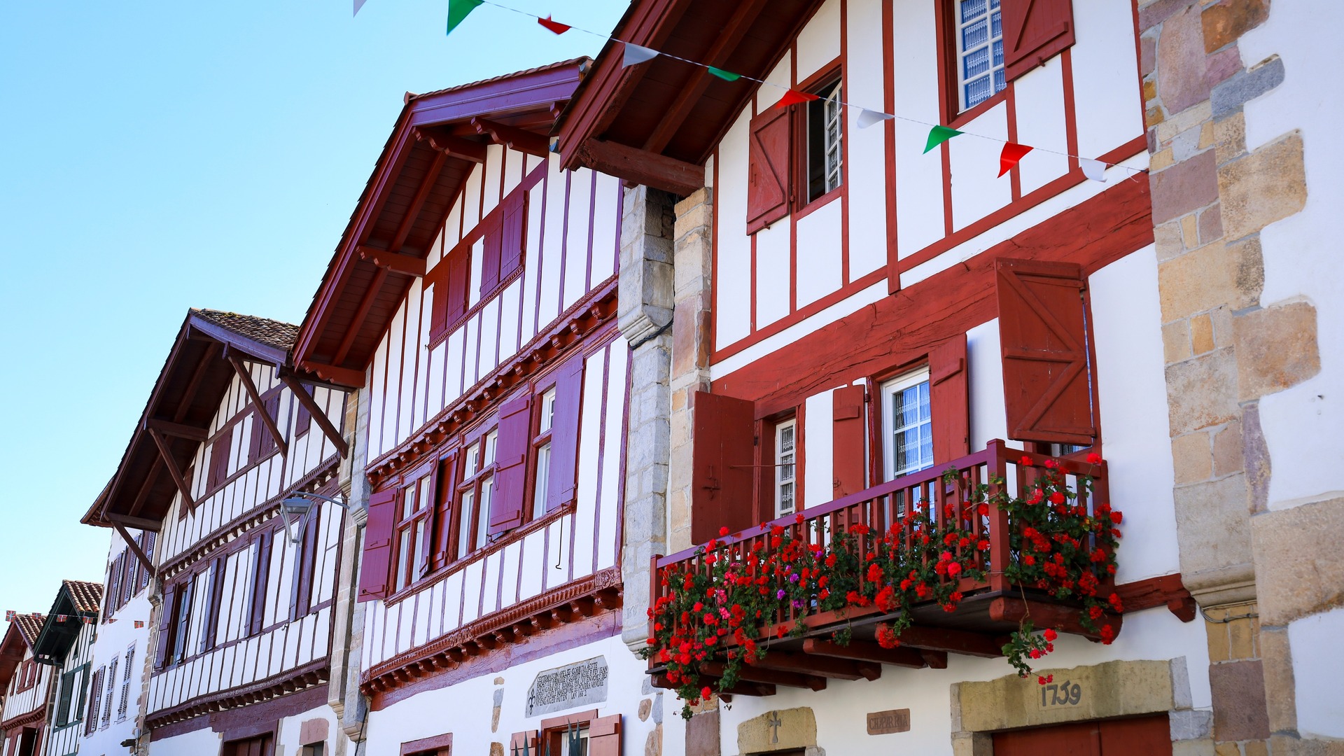 Casas tradicionales con entramado rojo y flores en balcones en Ainhoa, pueblo del País Vasco francés.