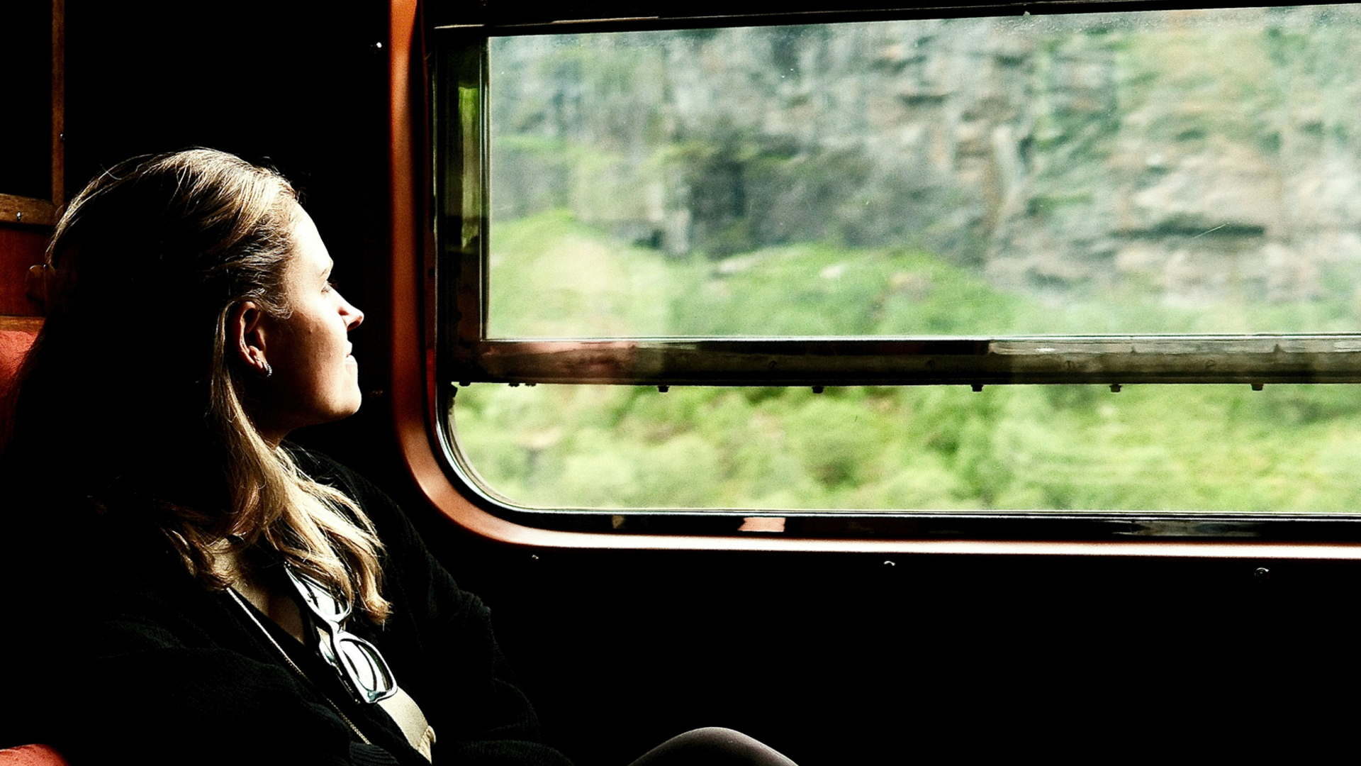 Mujer disfrutando de las vistas por la ventana del tren entre Oslo y Bergen, la famosa línea ferroviaria de Noruega.
