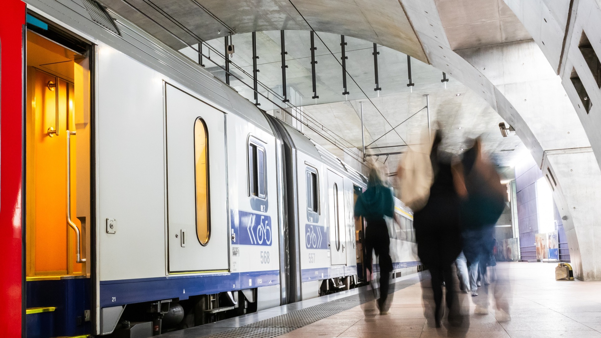 Andén moderno con tren y viajeros en la estación central de Amberes, Bélgica