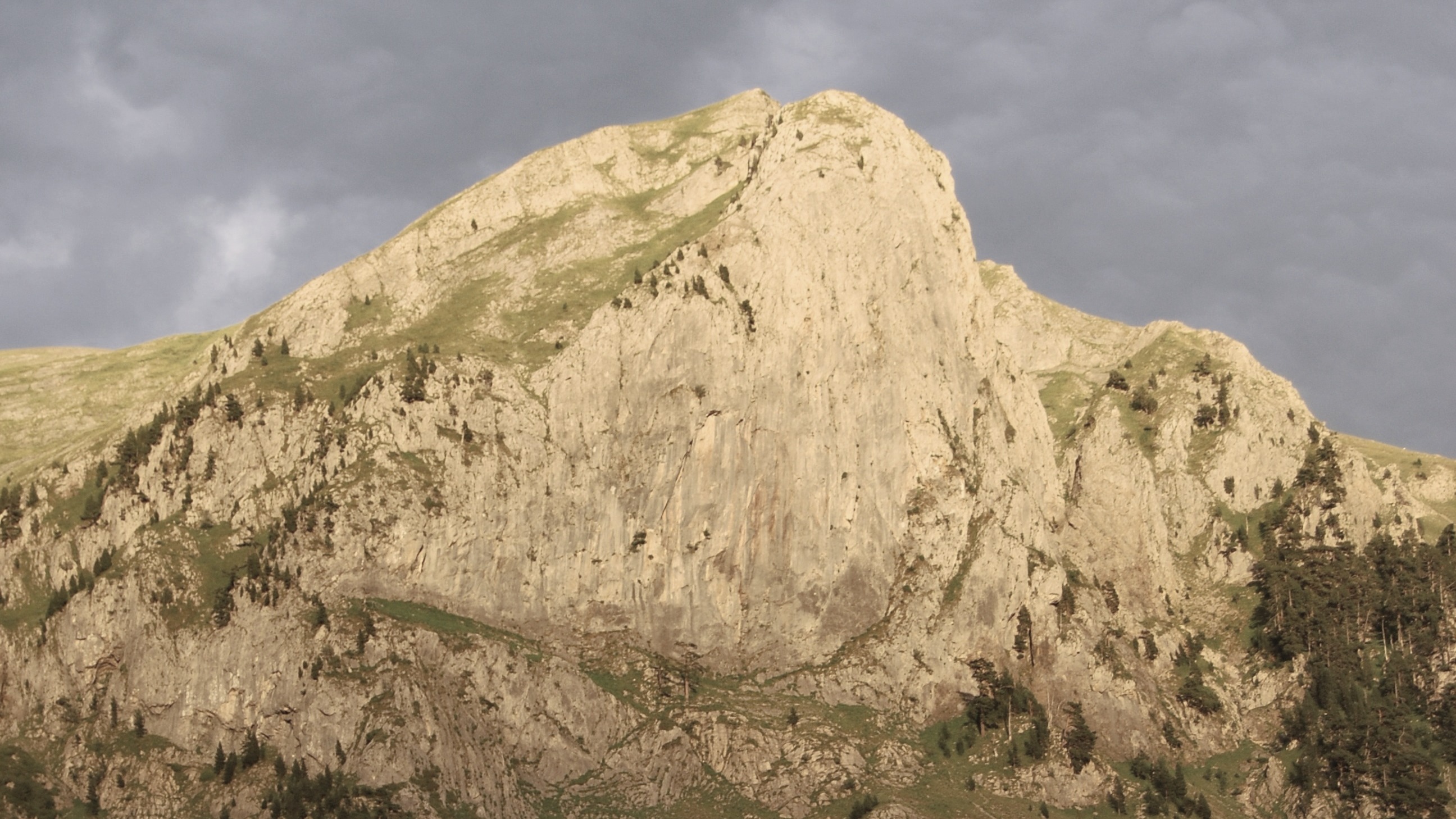 Pico de la Peña Oroel, un macizo rocoso y escarpado en los Pirineos cerca de Jaca, bajo un cielo nublado y oscuro.