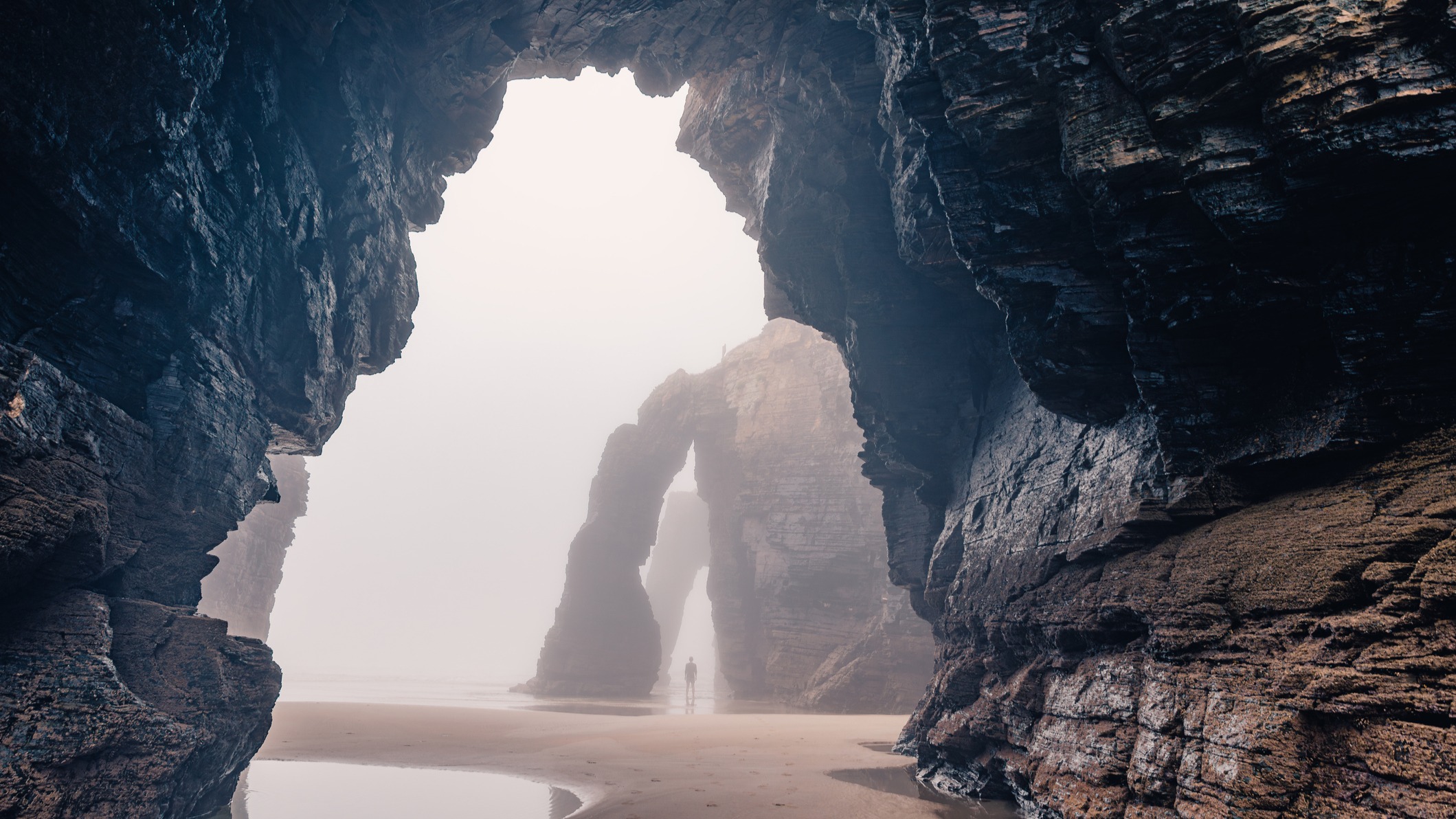 Vista interior de las cuevas y arcos naturales de la Playa de las Catedrales en un día de niebla, en la costa de Galicia.