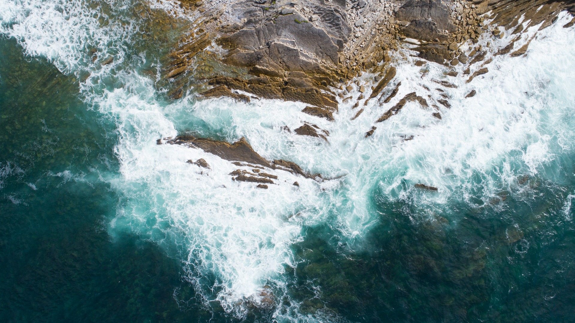 Olas rompiendo sobre rocas vistas desde arriba.