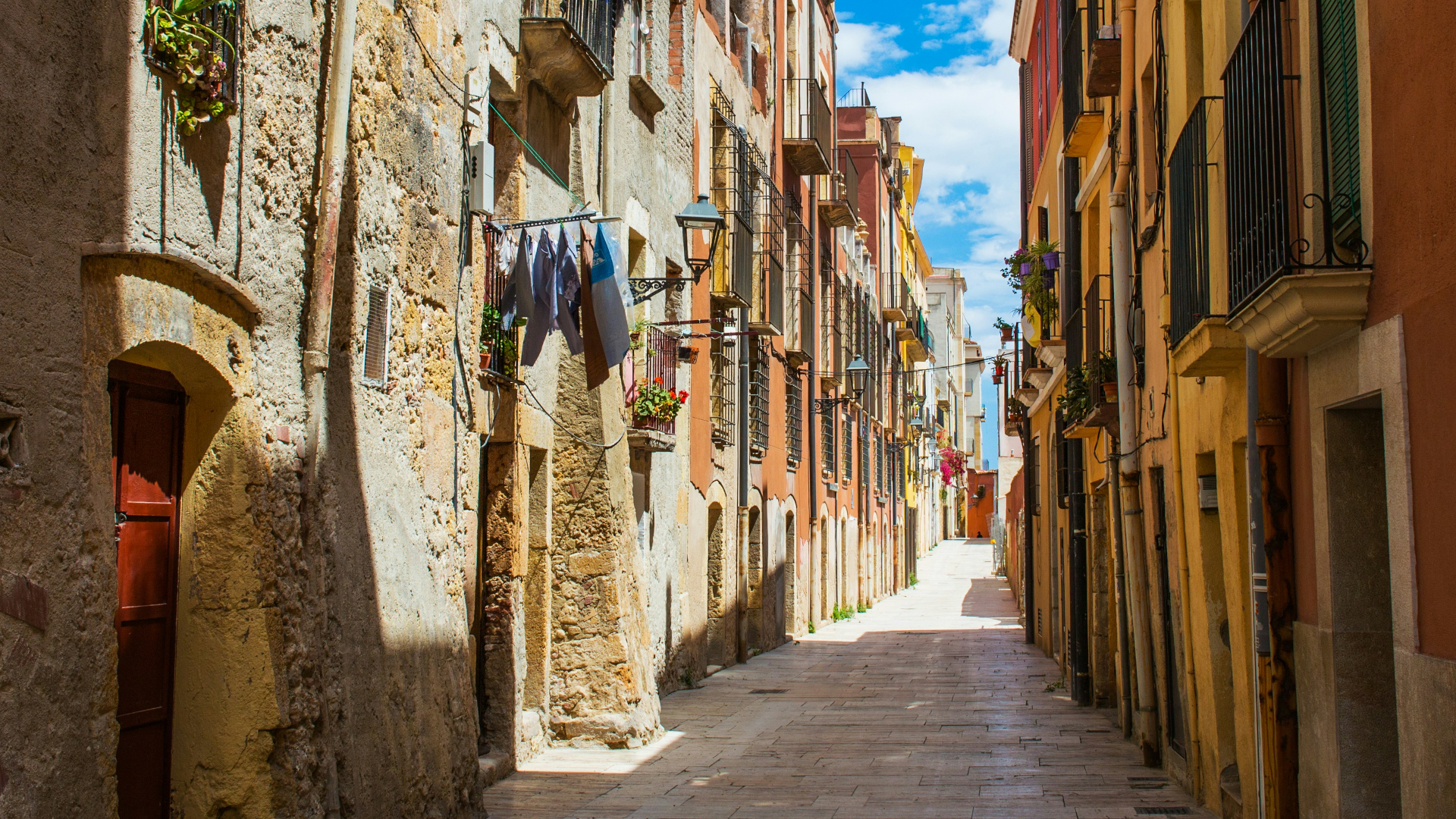 Callejuela estrecha soleada en el casco antiguo de Tarragona, con edificios de piedra y colores cálidos
