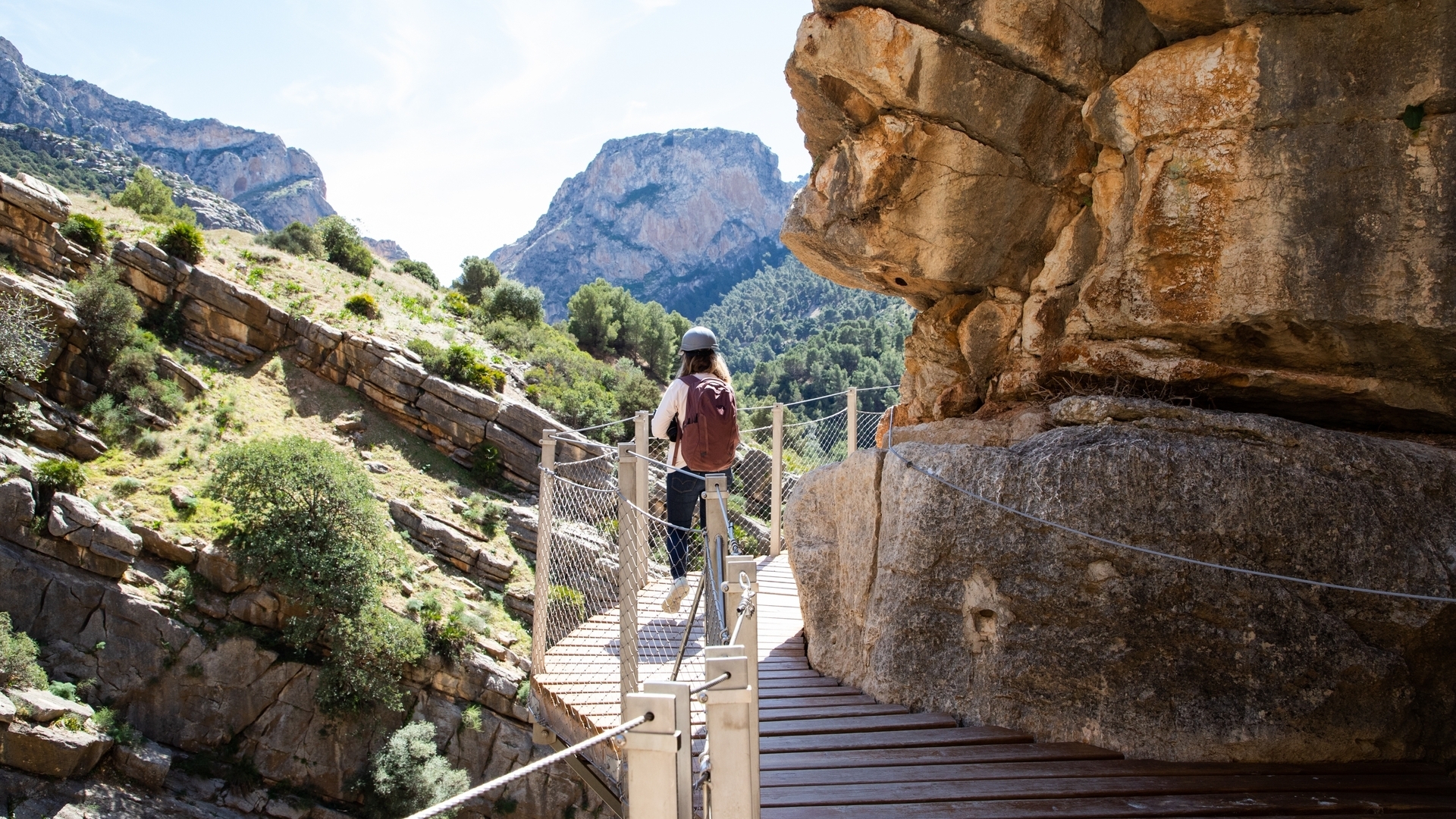 Mujer con casco y mochila caminando por la pasarela del Caminito del Rey