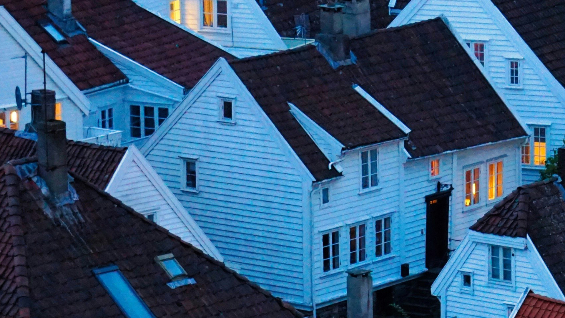 Casas tradicionales de madera blanca y tejados rojizos en Gamle Stavanger, Noruega, al atardecer.