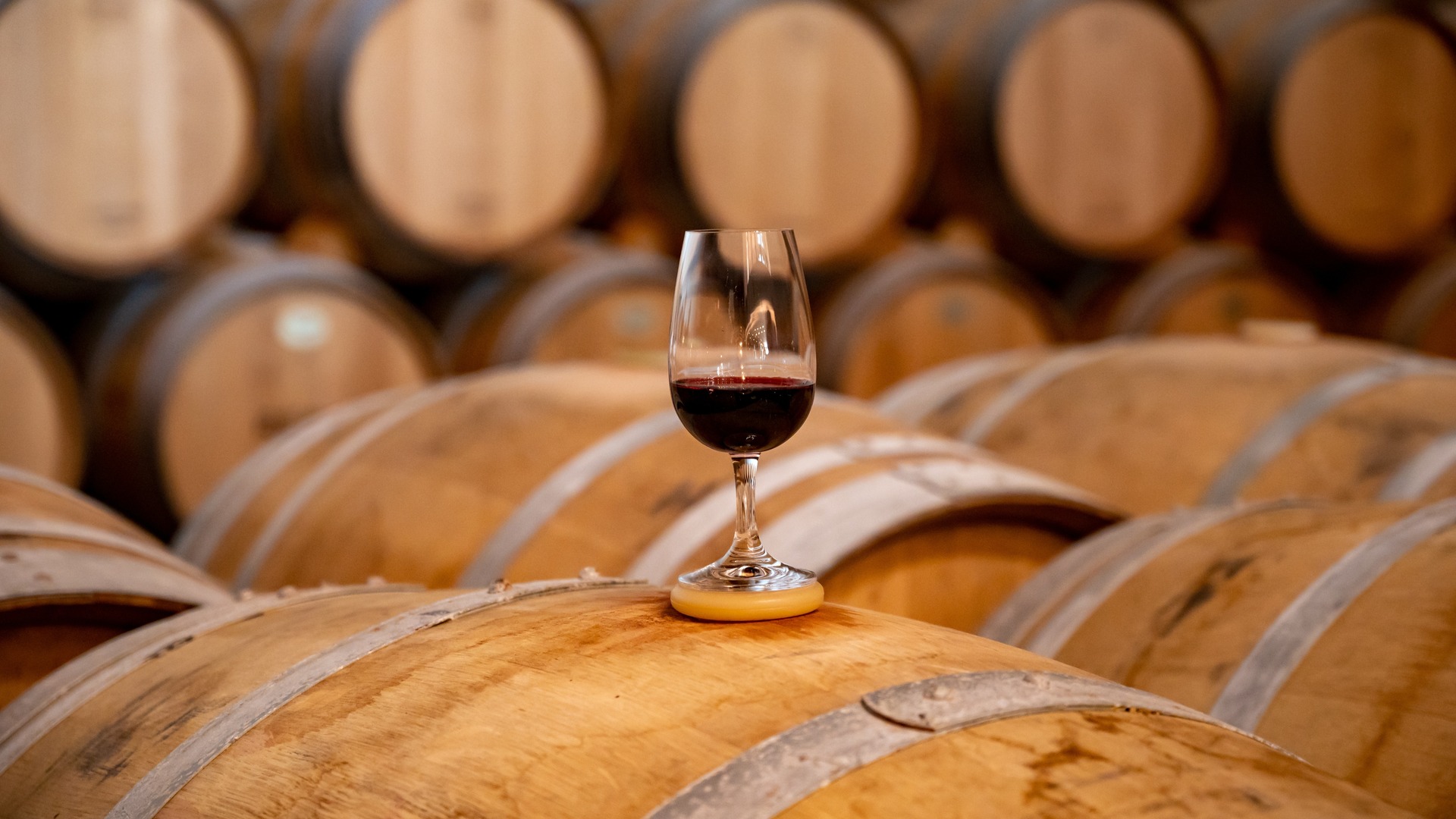 Copa de vino tinto sobre una barrica