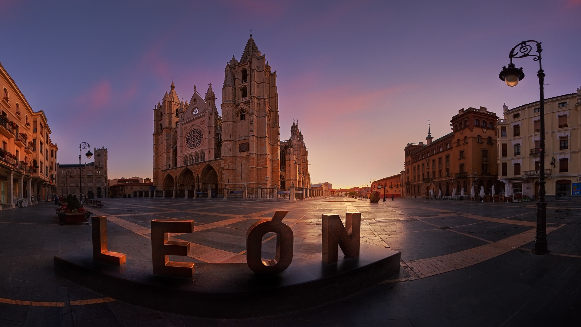 Catedral de León al amanecer, con el cartel de 'LEÓN' en primer plano, en la Plaza de la Regla, arquitectura gótica.