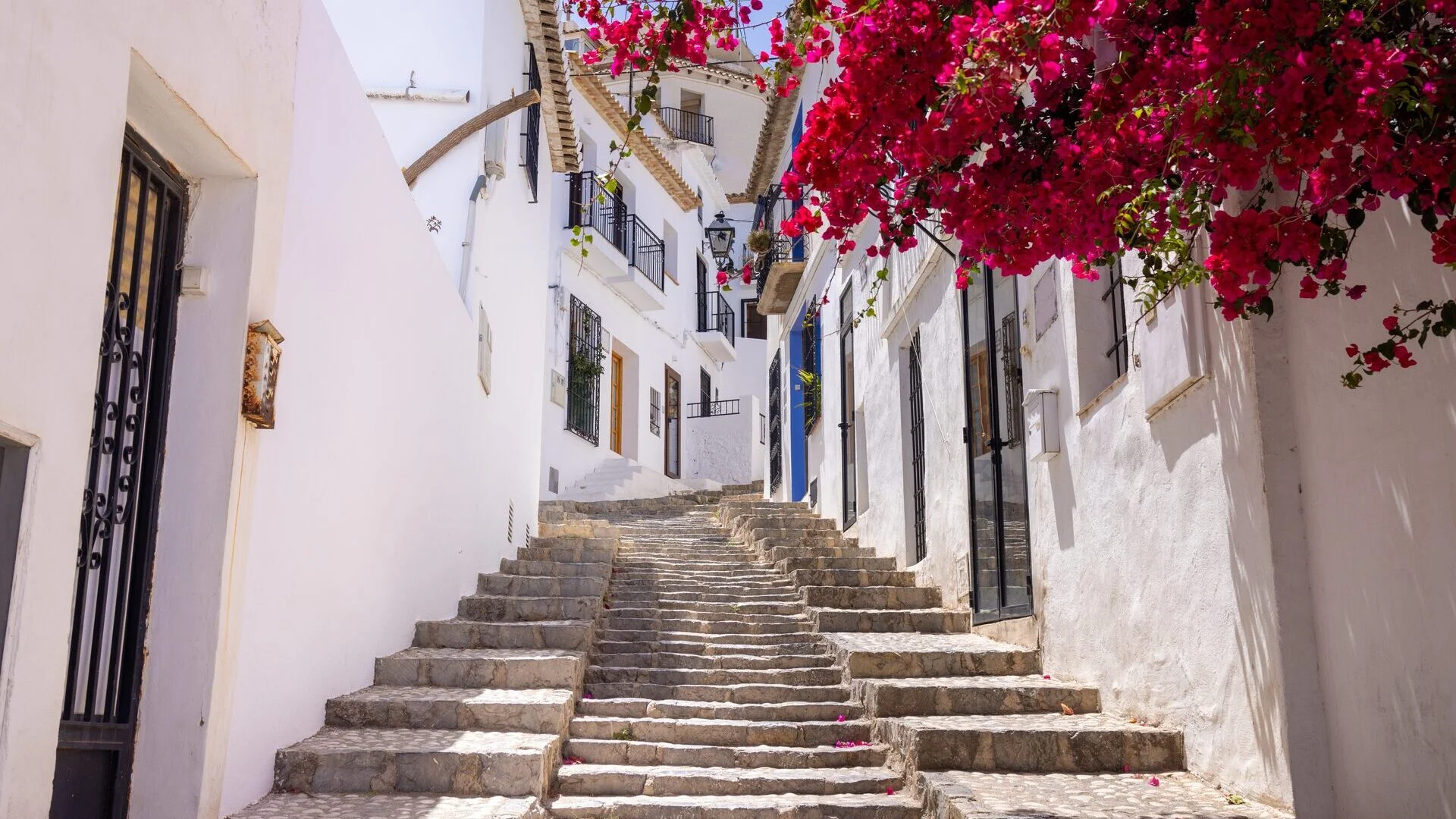 Calle escalonada con casas blancas y buganvillas en el casco antiguo de Altea
