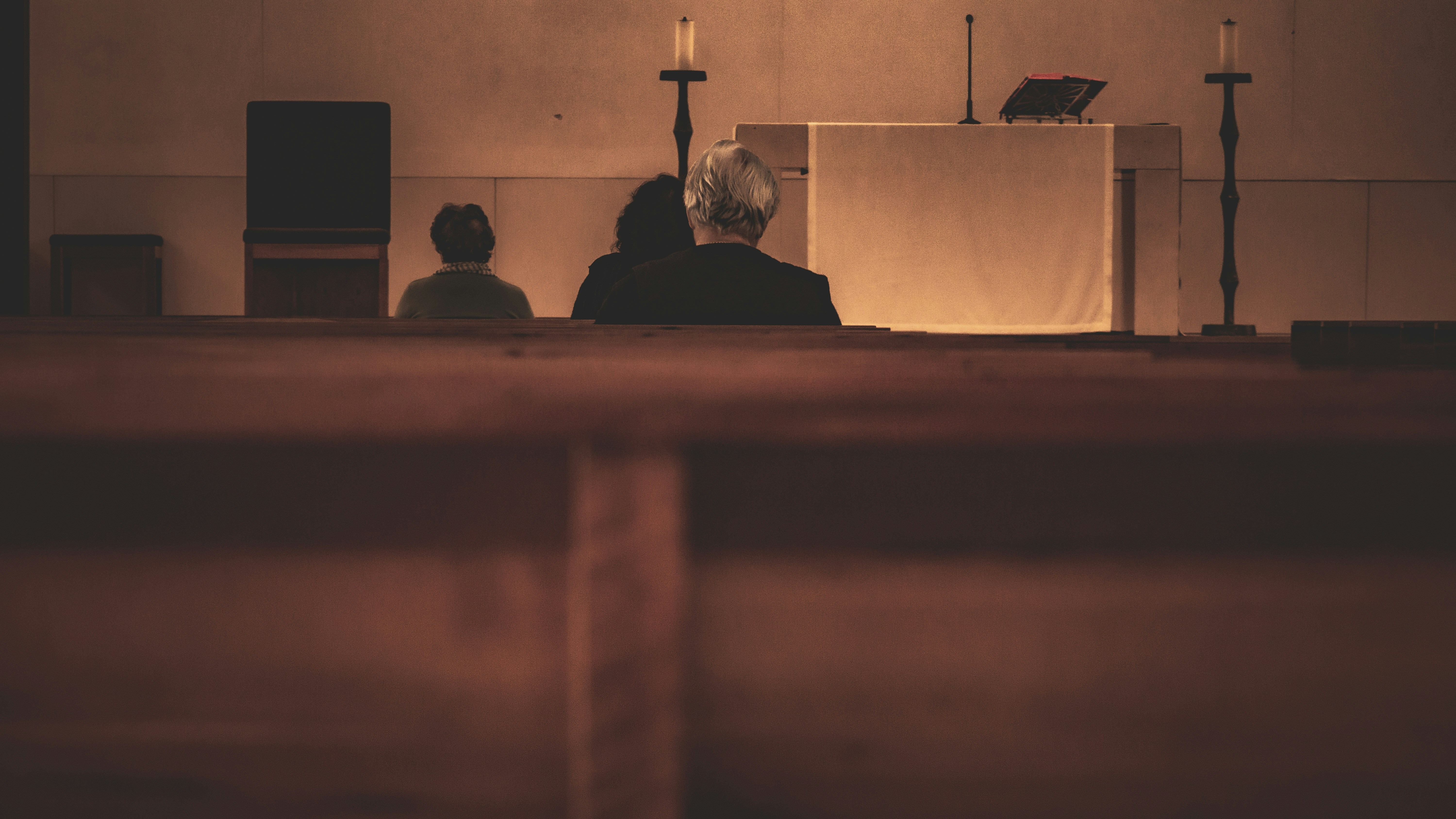 Fieles rezando o asistiendo a misa en una iglesia de Fátima, vista trasera de la congregación y el altar.