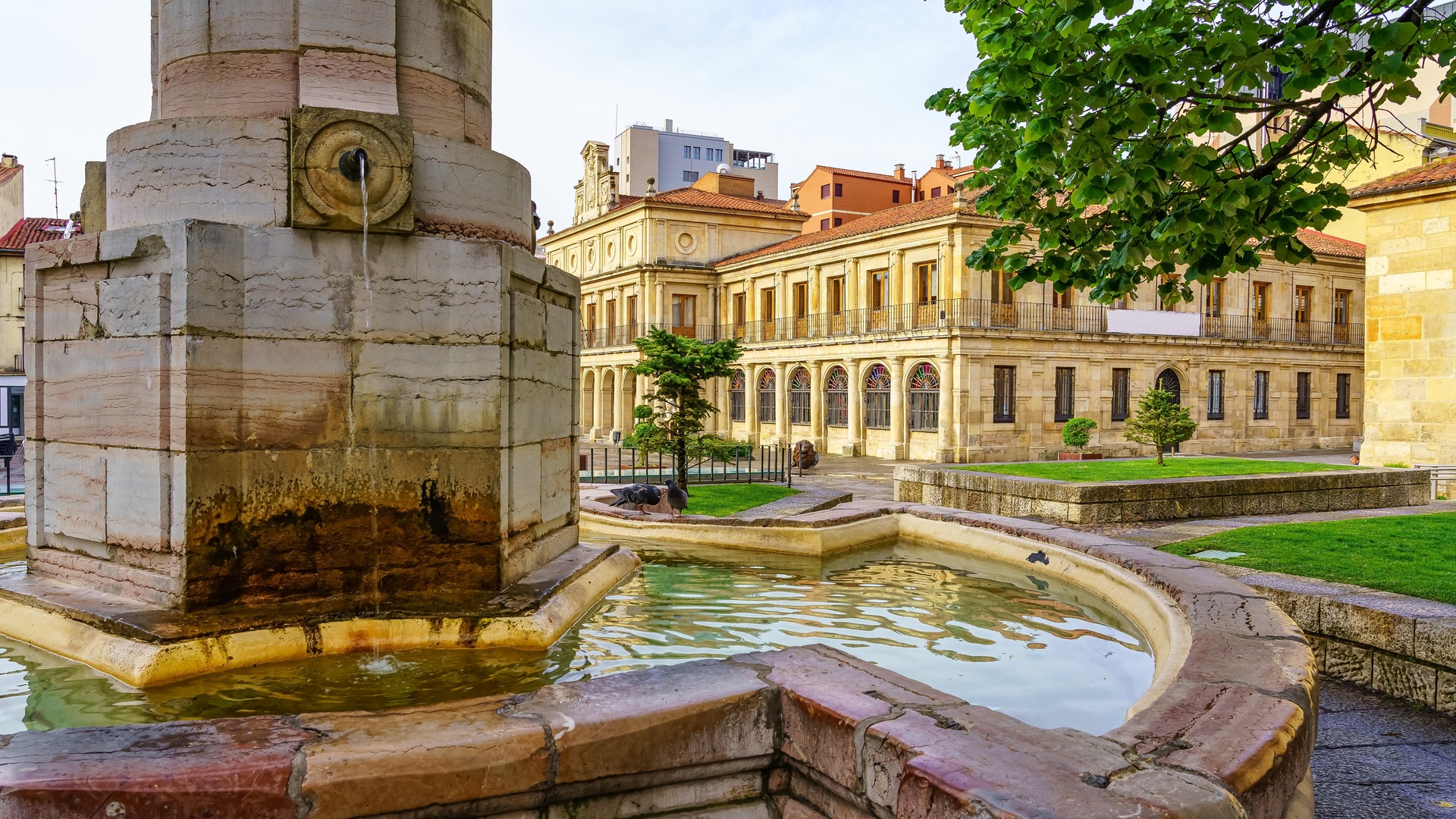 Fuente histórica en la Plaza San Isidoro, León, con el Real Colegiata de San Isidoro, arquitectura románica y jardines.