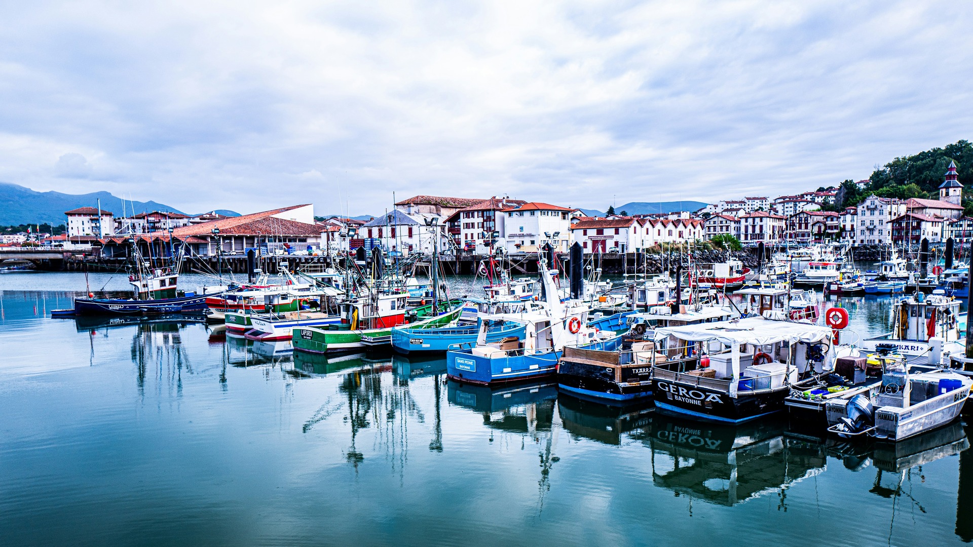 Puerto de San Juan de Luz con barcos de pesca y casas tradicionales junto al agua.