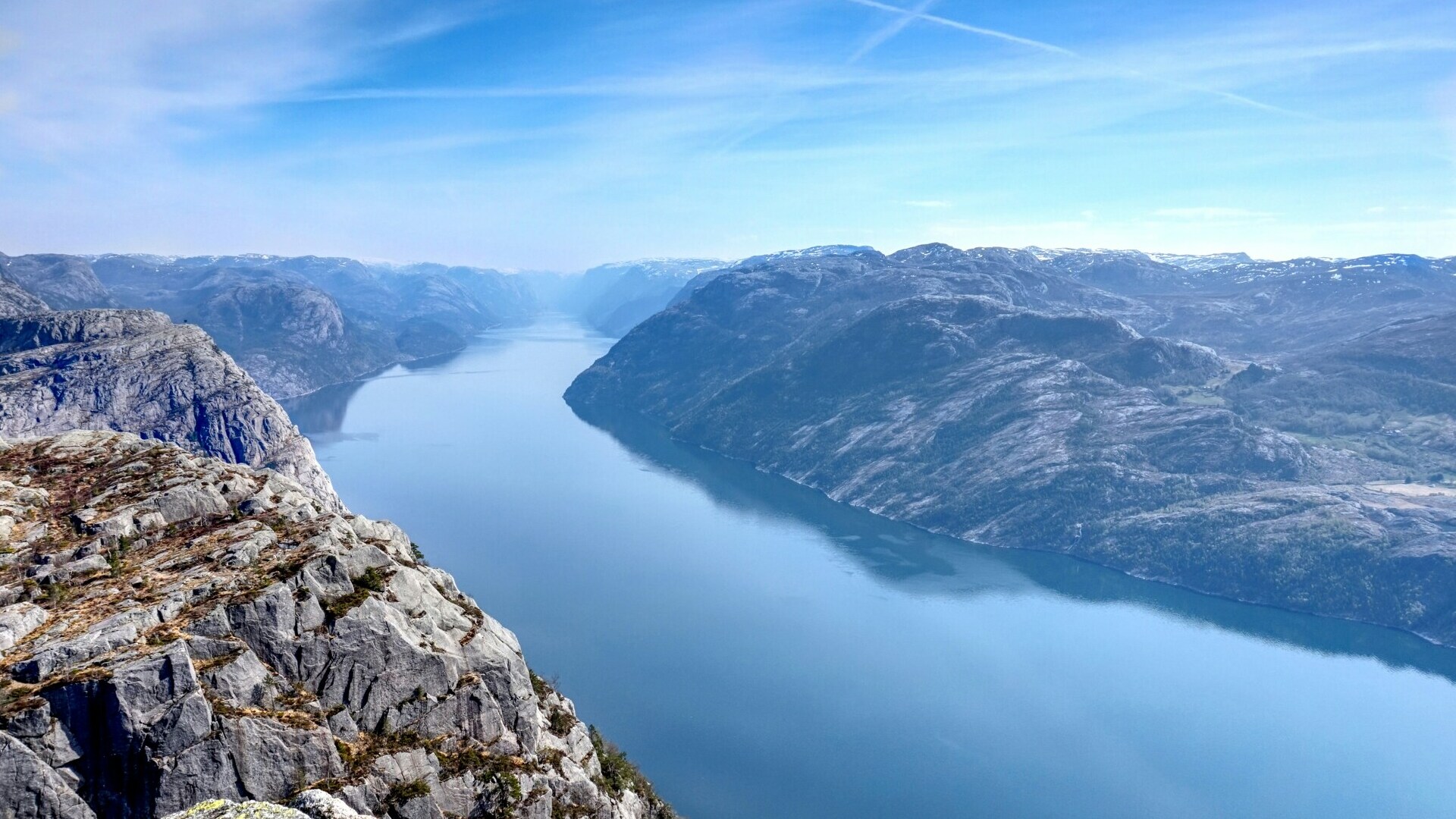 Vista panorámica del fiordo Lysefjord en Noruega, con acantilados rocosos y aguas tranquilas bajo cielo despejado.